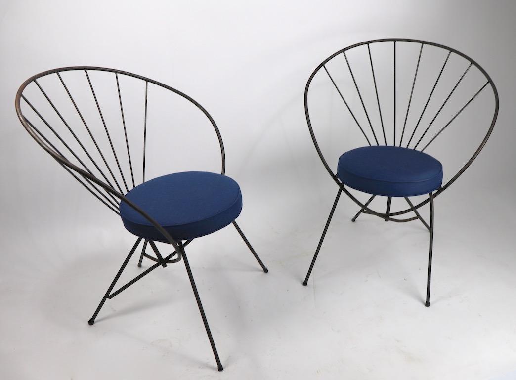 Paire de chaises élégantes en fer forgé du milieu du siècle dernier, avec dossier en forme de cerceau et sièges rembourrés récemment (tissu Sunbrella bleu). Les deux chaises sont en très bon état de propreté et ne présentent qu'une usure cosmétique
