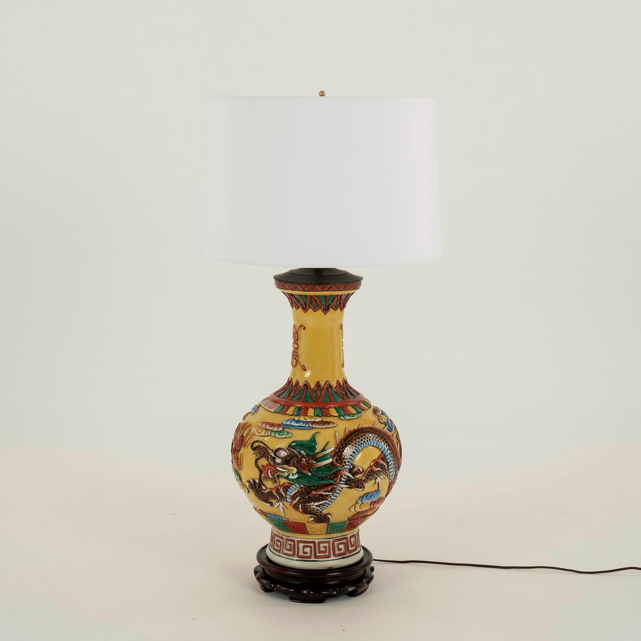 Pair carved porcelain gourd lamps with white shades. Intricately incised porcelain detailed with bold multi colored auspicious dragons, clouds and greek key over a bold yellow background.