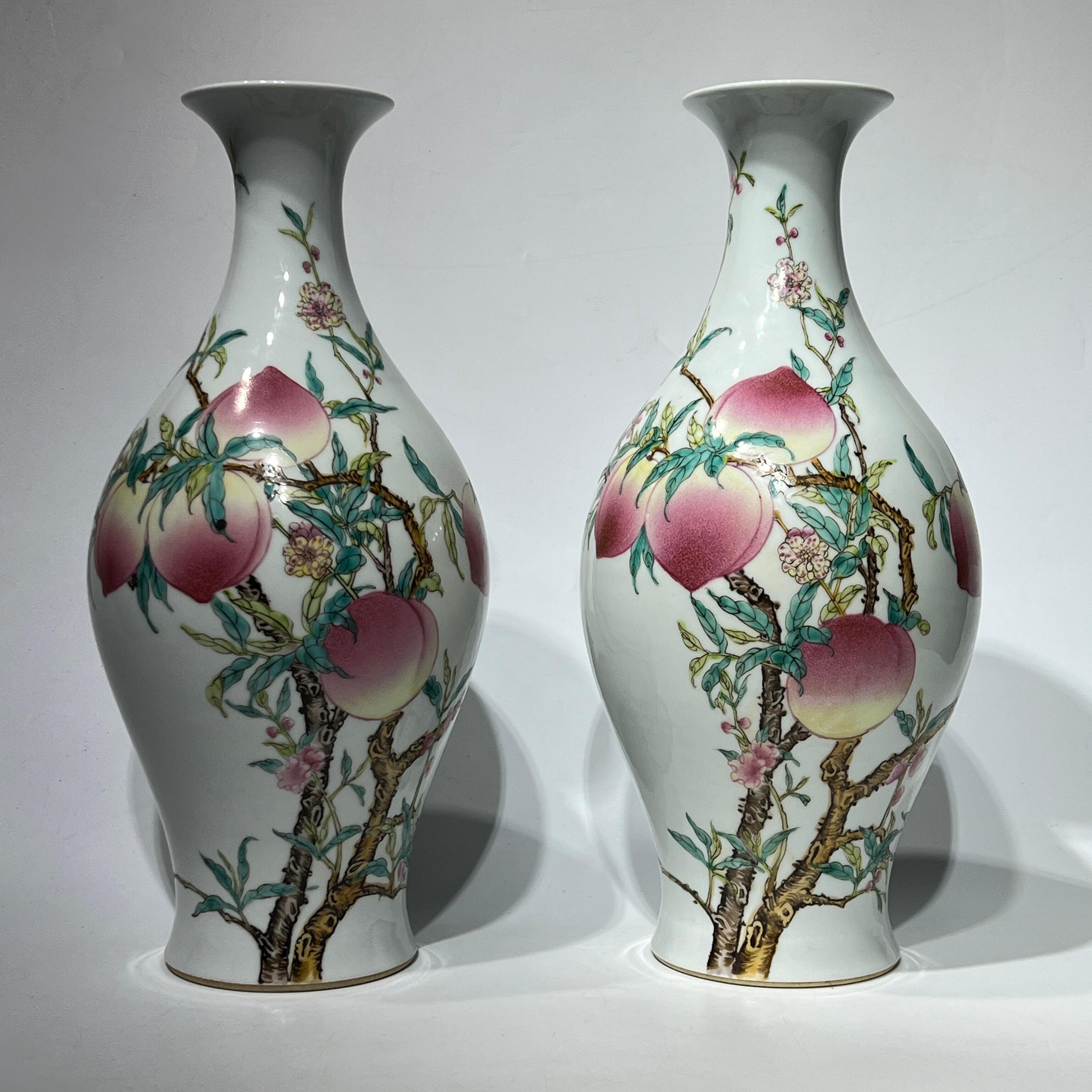 Pair of vintage Chinese export porcelain vases with beautiful peach designs, each 16.5 by 7 inches with marks of the Yongzheng period (1678-1735) of the Qing Dynasty. Each in excellent condition. 