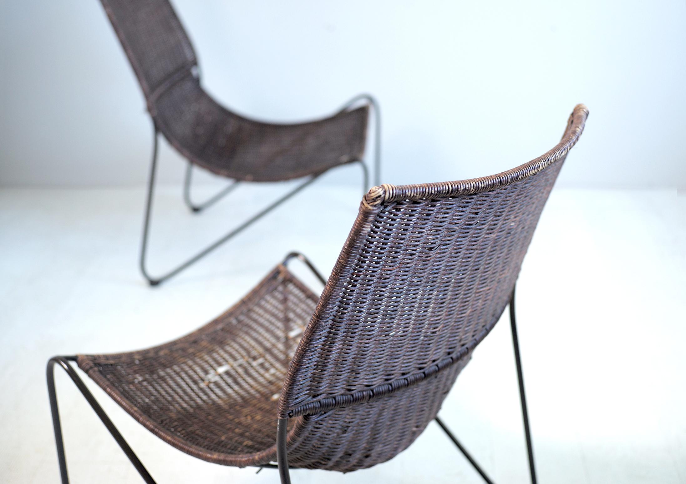 Elegant pair of woven rattan fireside chairs attributed to Frédéric Weimberg on a blackened round iron frame, France 1950. The free-form base is in curved and patinated iron. Superbly designed, these armchairs are a fine example of the creativity of