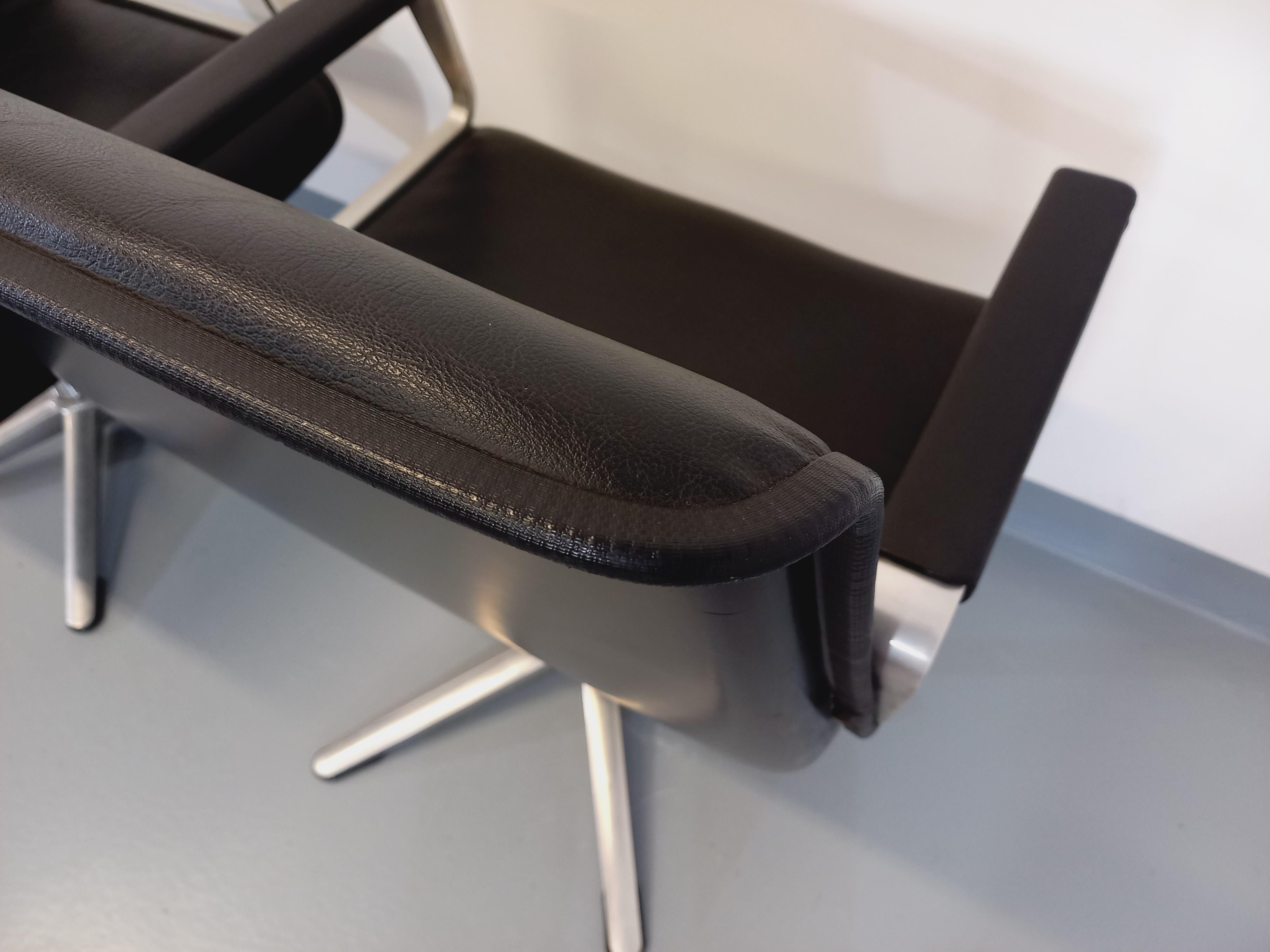 Suite de 2 fauteuils de bureau vintage des années 70 avec accoudoirs, fauteuils de conférence ou de direction vintage, de marque allemande Wilkhahn, en skai noir et fonte d’aluminium. 
Pieds centraux différents : le premier fauteuil peut être