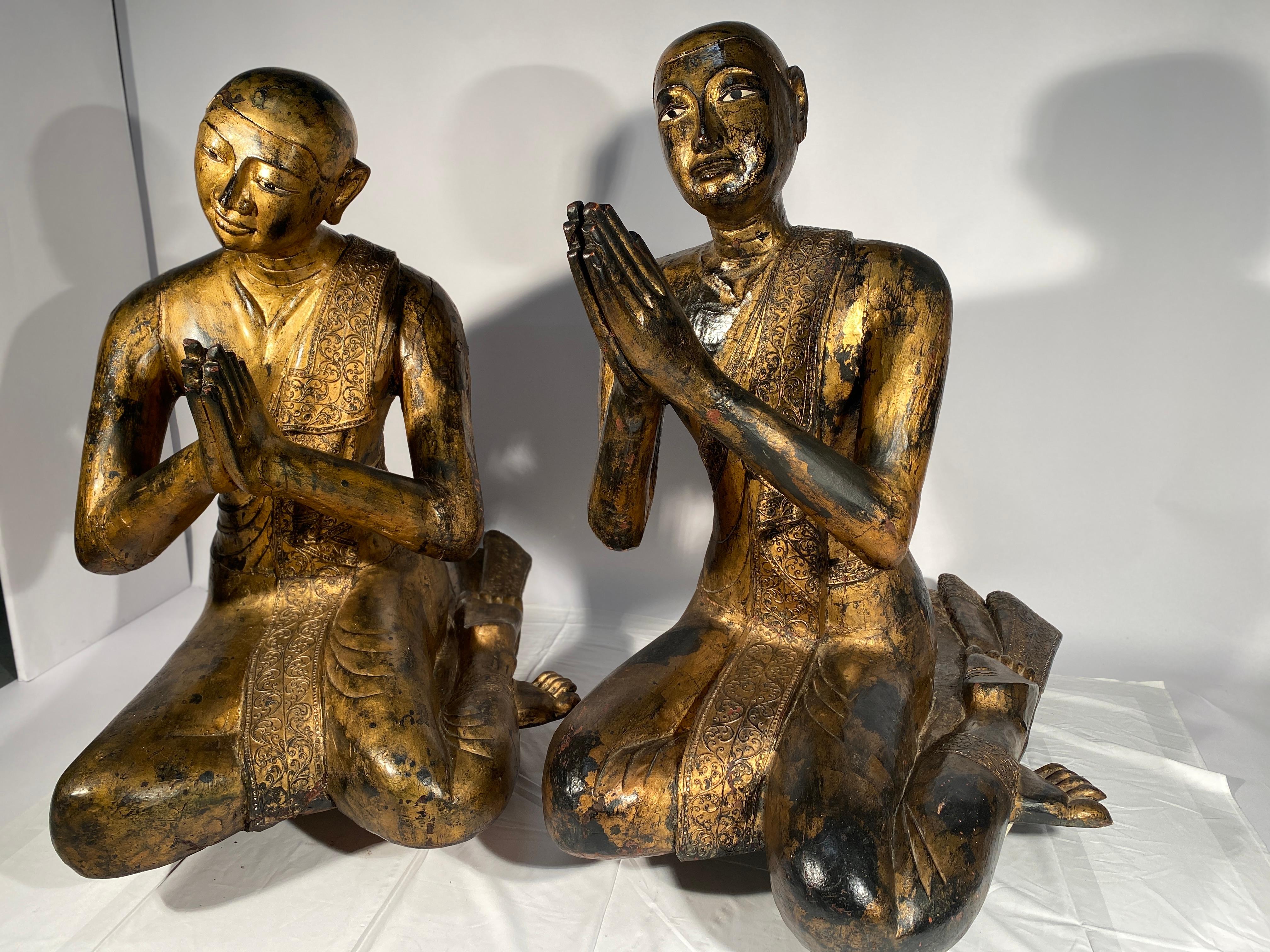 Importante paire de moines priant en bois laqué et doré. Ils sont en pendants, ils ont en effet chacun leur tête légèrement inclinée l'une vers l'autre. Leurs tailles sont exceptionnelles puisqu'ils mesurent respectivement 108 et 114 cm de