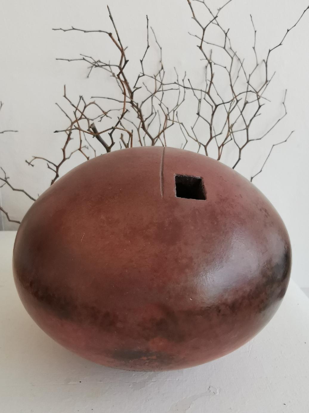 Two ceramic spheres flattened, raku cooking, two different sizes, a little square hole on them to contrast with the shape of the objects; the spheres are made of stoneware . The two ceramic spheres are covered with ash and cooked at low temperature