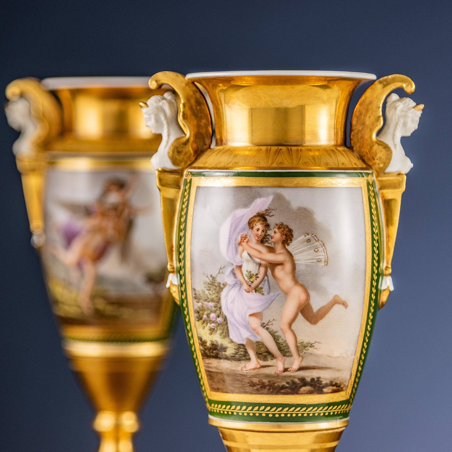 Paire de vases en céramique reposant sur une base en marbre noir belge ; avec deux anses en forme de cariatides ailées. Les vases sont partiellement dorés et émaillés en vert avec des motifs de style Empire, tels que des motifs de feuilles grecques
