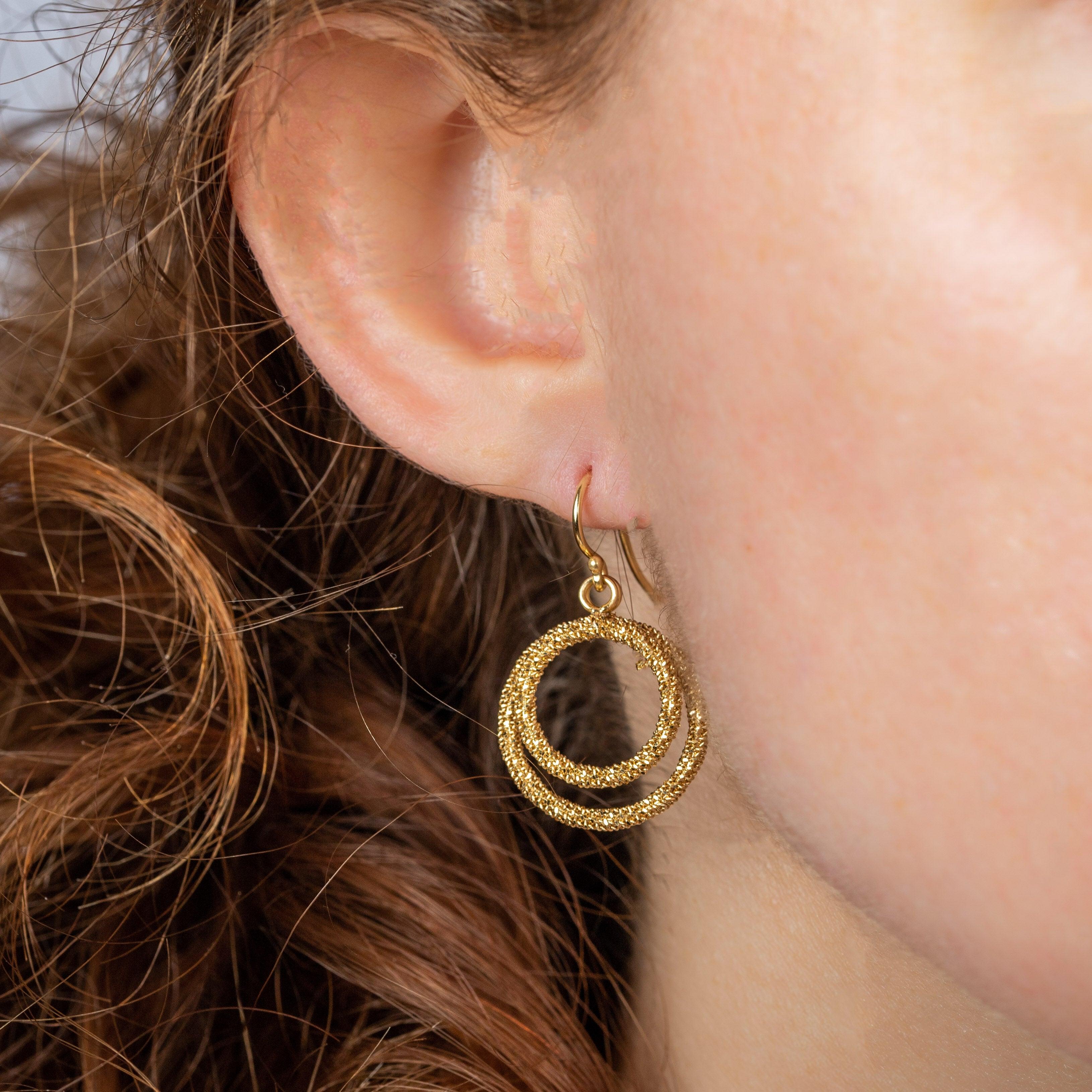 Slender whispers of hand-woven gold, these light and lovely earrings play with negative space to make a compelling statement. Each duo of open circles is meticulously crafted from diamond-cut 18K yellow gold chain for a richly textured effect that