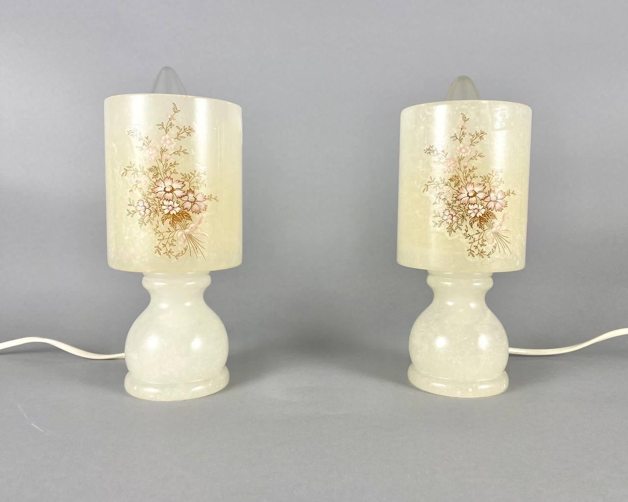 Kleine Tischlampen aus Marmor.

 Gepaarte Nachttischlampen mit schönem Blumendekor auf zylinderförmigen Schirmen.

Beide sind komplett aus Marmor gefertigt, was für die schöne natürliche Transluzenz sorgt. Dies verleiht den Lampen ihren Charme.

 Es