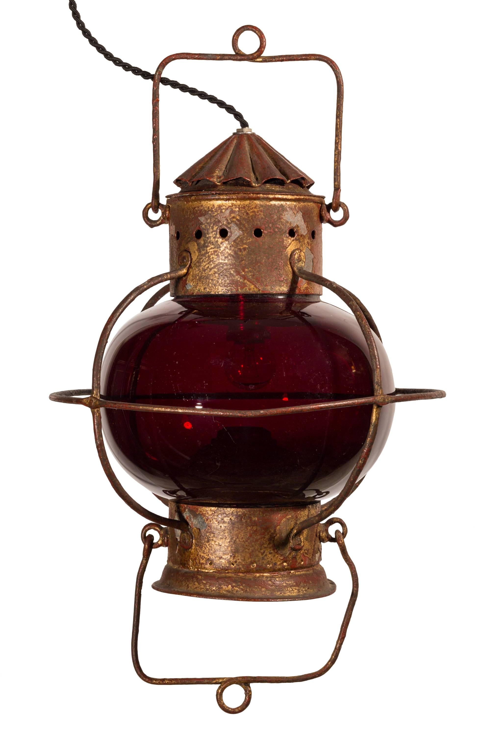 Unmatched pair of late 19th century nautical oil lamps with pristine red globes.
Similar in size and shape, these two lamps originally used a kerosene or oil flame for illumination, and the reservoir and wick assembly are included.
Both have been