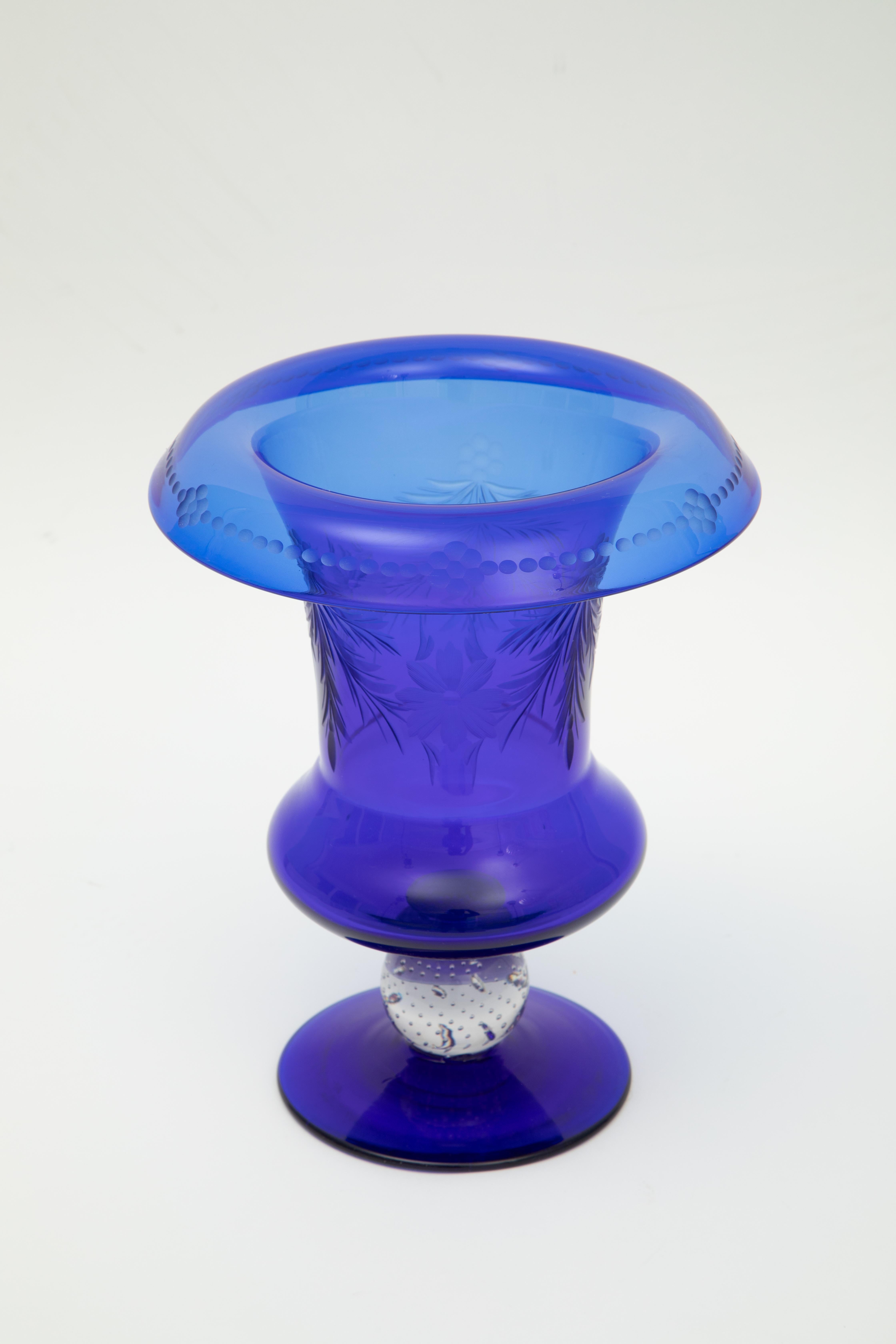 A vibrant and elegant blown crystal vase by one of our favorite Gilded Age Glassworks, Pairpoint. This lovely piece features wheel engraved designs in the main cobalt blue body and of course their signature controlled bubble stem. In wonderful