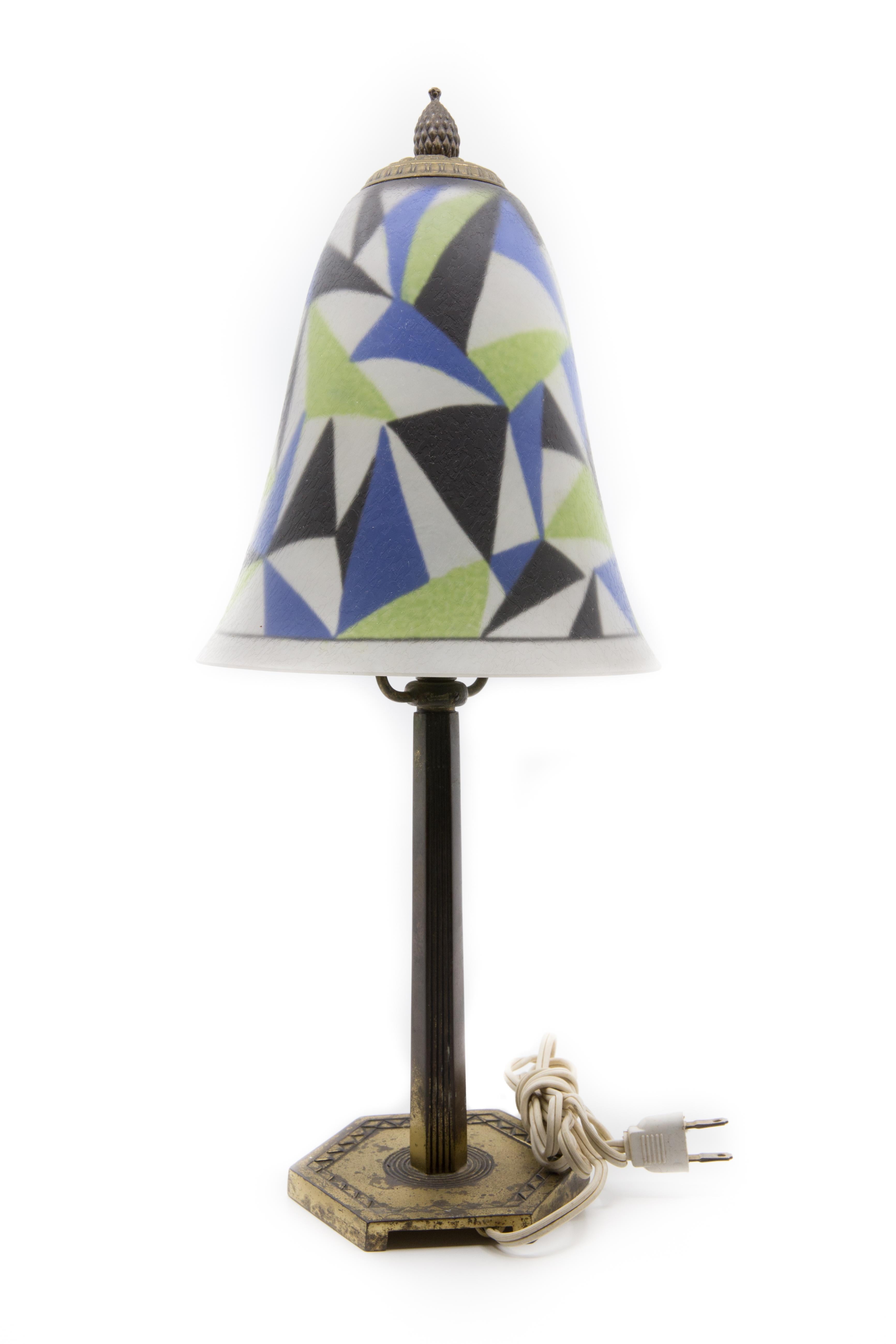 Offered is a rare signed art deco reverse painted Pairpoint desk lamp, circa 1925. The etched reverse painted lamp shade is painted on the reverse with geometric designs. It is mounted on a geometric form bronzed base. The lamp is signed shade and