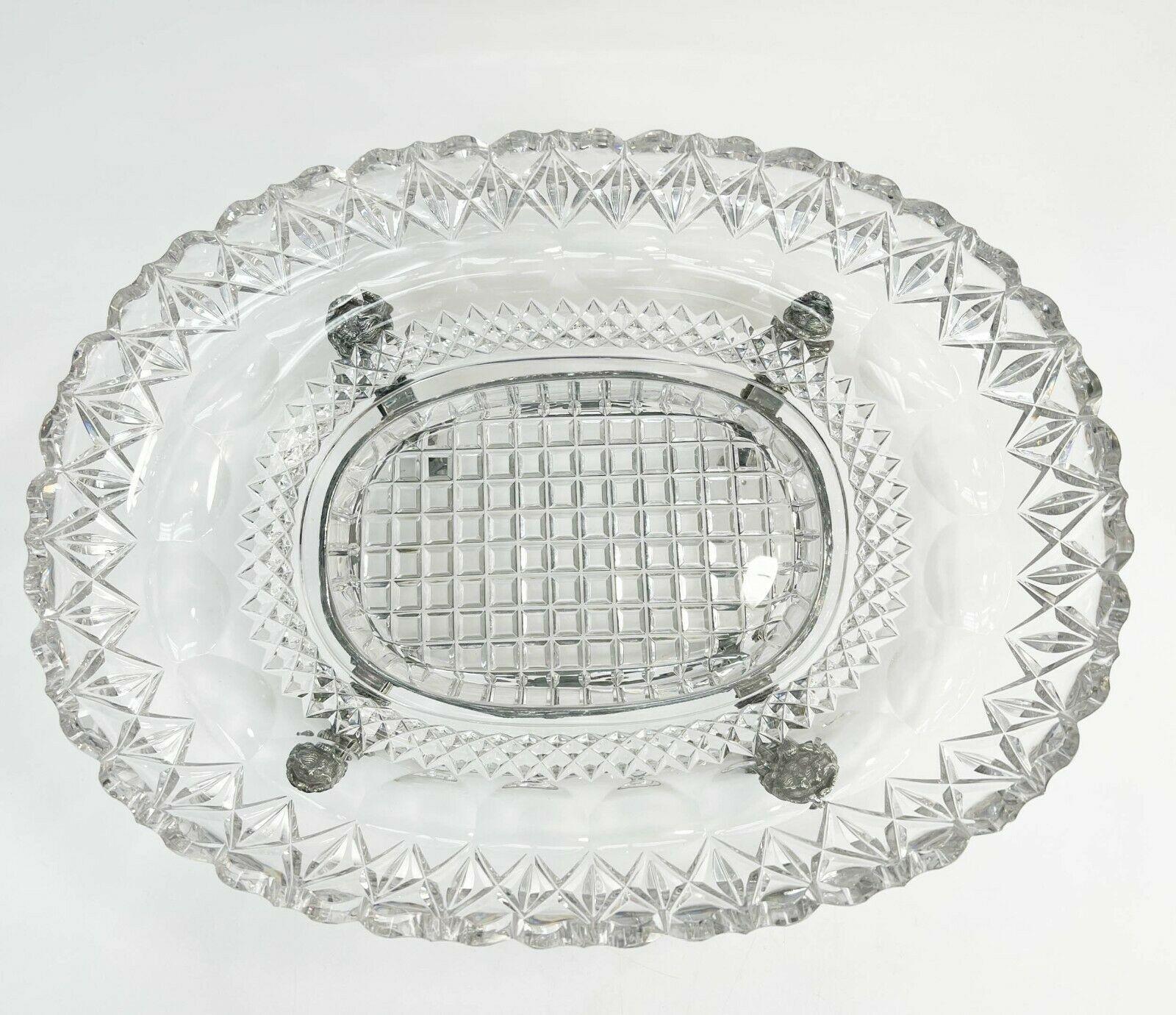 Pairpoint silverplate and cut glass centerpiece bowl, circa 1920

Silverplate mounted glass bowl with a cut geometric pattern. Silverplate mount with foliate decoration and figural heads. Figural animalistic feet. Garlands, ribbons, and pendant