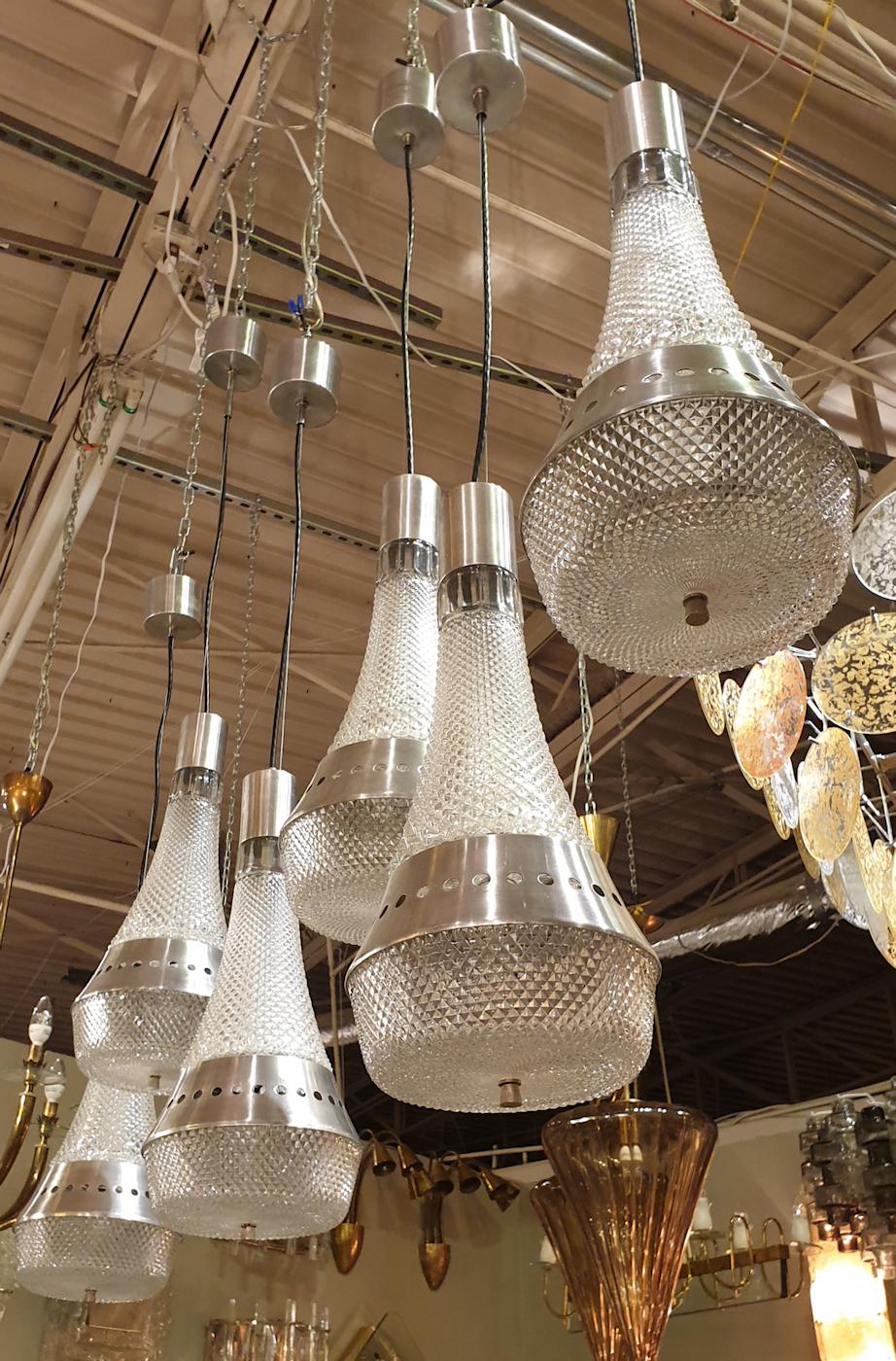 Three pairs of Italian, Mid-Century Modern,  pendant chandeliers, circa 1970s.
The six vintage pendant lights are made of clear diamond pattern glass and brushed steel.
The pendants have 2 lights each, illuminating the two up and down glasses; and