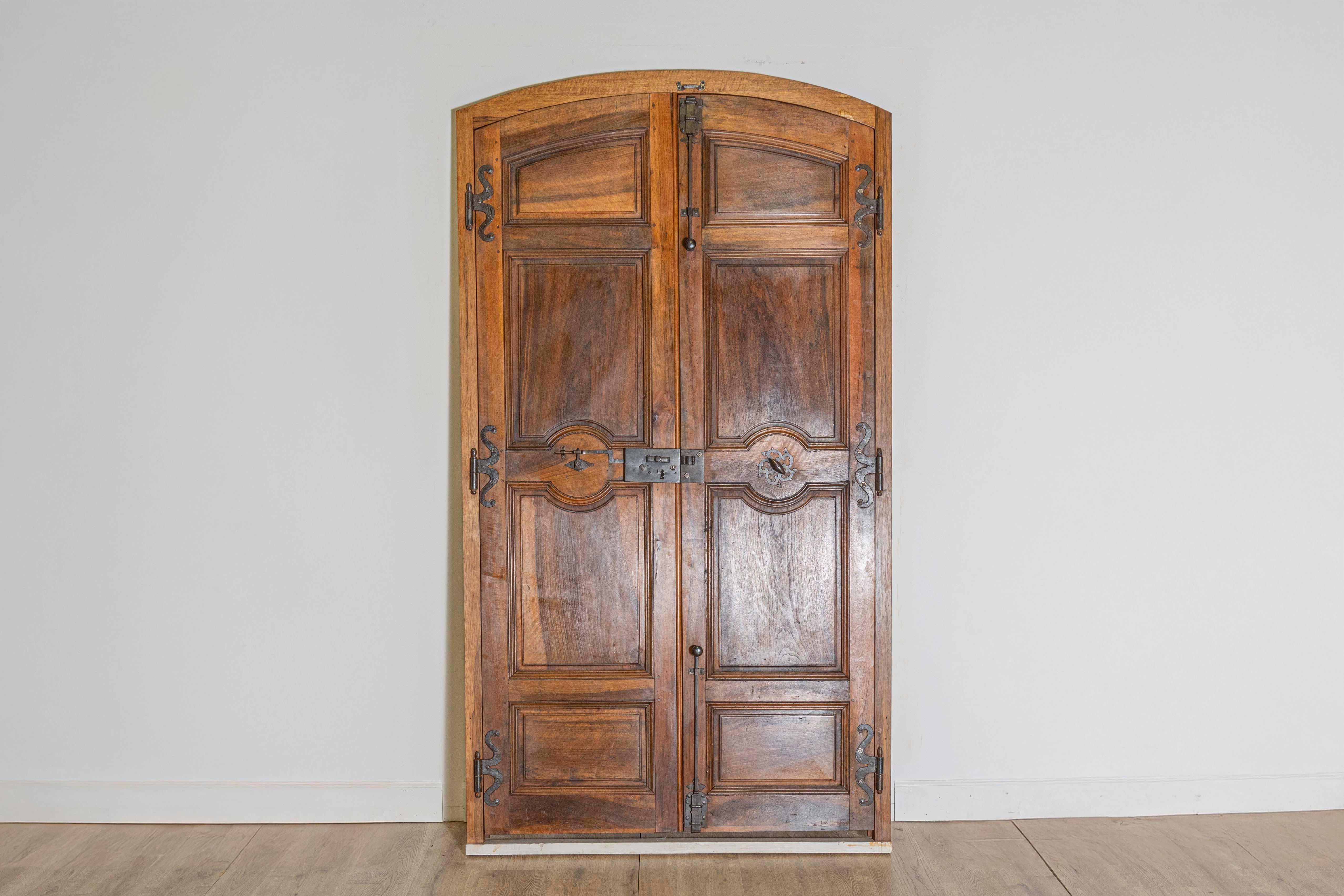 Questa squisita coppia di porte di comunicazione francesi della fine del XVIII secolo, circa 1790, mostra la raffinata maestria tipica dell'epoca. Le porte sono realizzate in legno scuro e ricco, con pannelli intricati e piani graziosamente arcuati