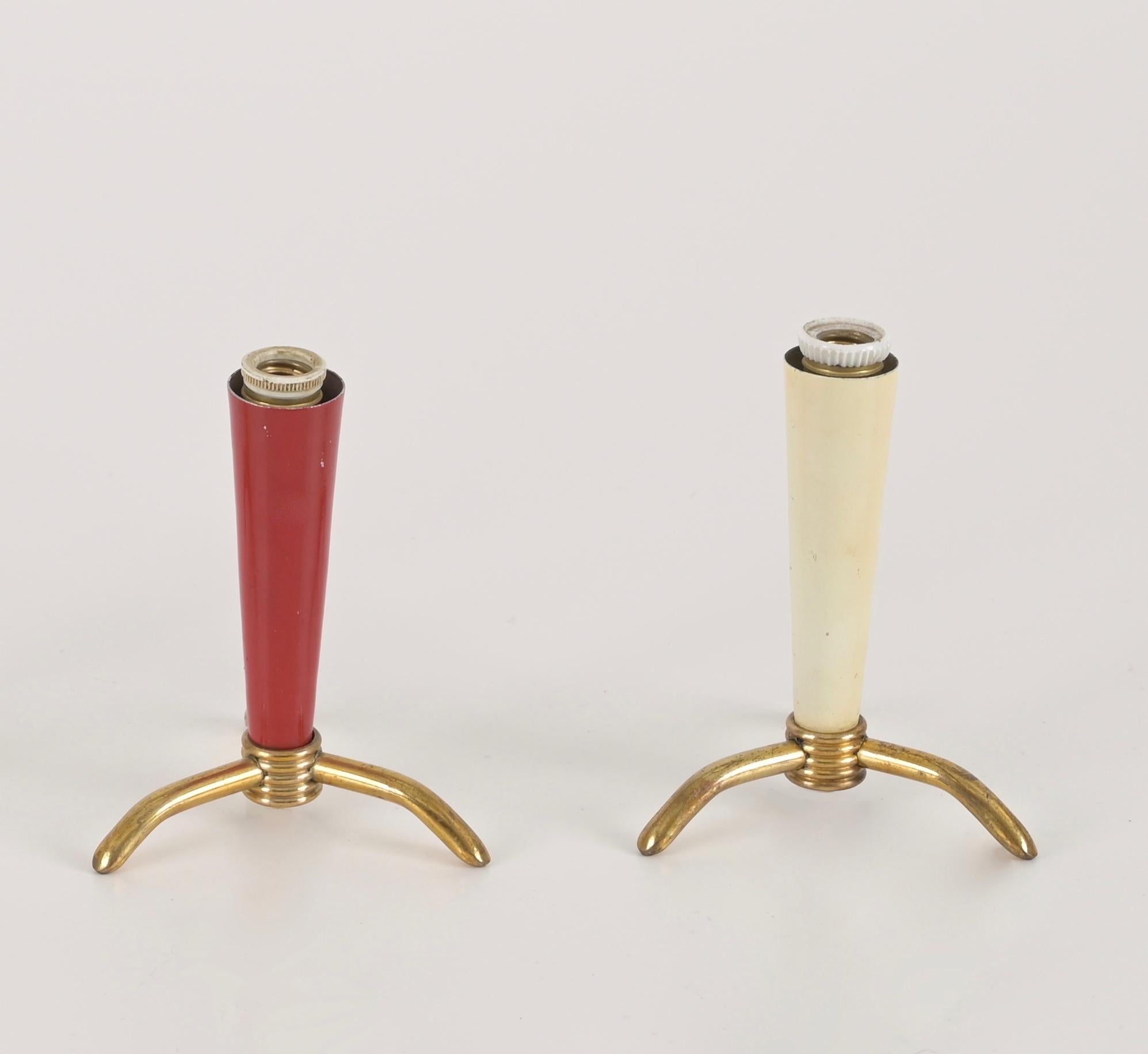Charmantes Paar dreibeiniger Tischlampen aus Messing und emailliertem Metall. Diese schönen Lampen werden Stilnovo zugeschrieben und wurden in den 1950er Jahren in Italien hergestellt.

Die kleinen Lampen haben einen reizvollen kegelförmigen Schirm