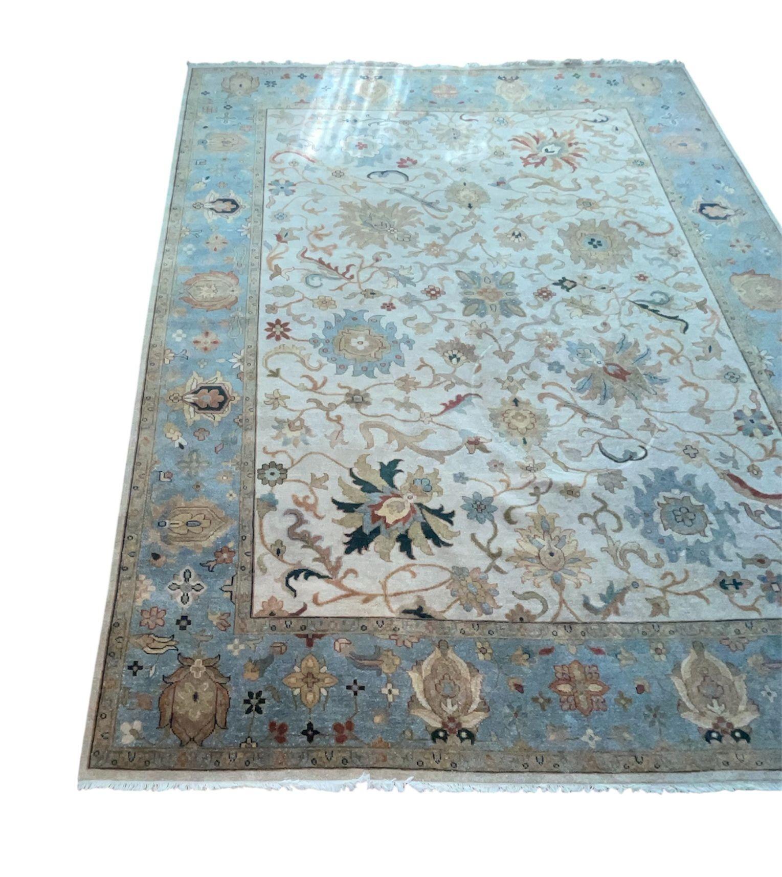 Un tappeto di grandi dimensioni tessuto nella tradizione Sultanabad/Mahal, caratterizzato da un reticolo a tutto campo di palmette, rosette e tralci che scorrono. La tavolozza abbina un morbido campo avorio a un bordo principale azzurro, con accenti