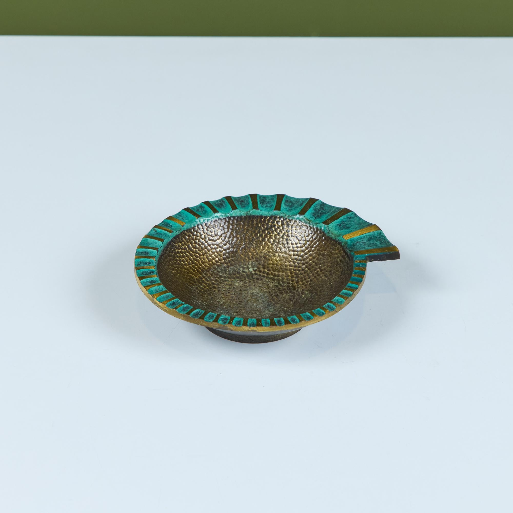 A heavy, cast bronze ashtray by Maurice Ascalon in a nautilus shape has a fluted, flat edge that widens as it spirals around the well, which has a hammered texture. The concave portions of the fluting are finished with a verdigris patina that