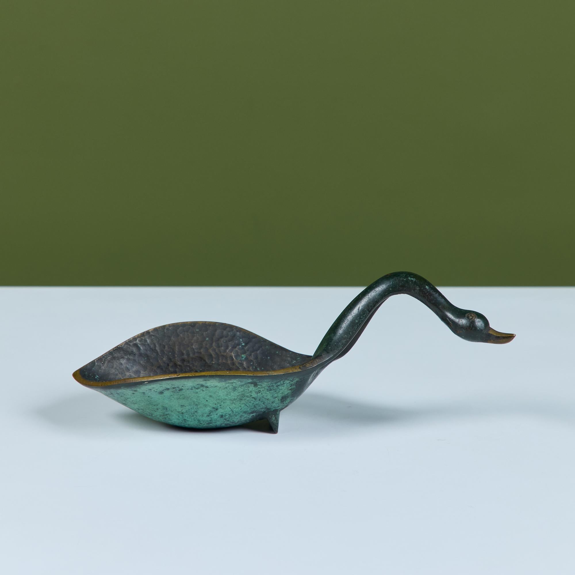 Cuenco de bronce en forma de cisne de Pal-Bell. La pieza presenta un cuello curvado y una pátina verdigris con un interior martillado y un pozo profundo para baratijas o llaves.

Dimensiones
10
