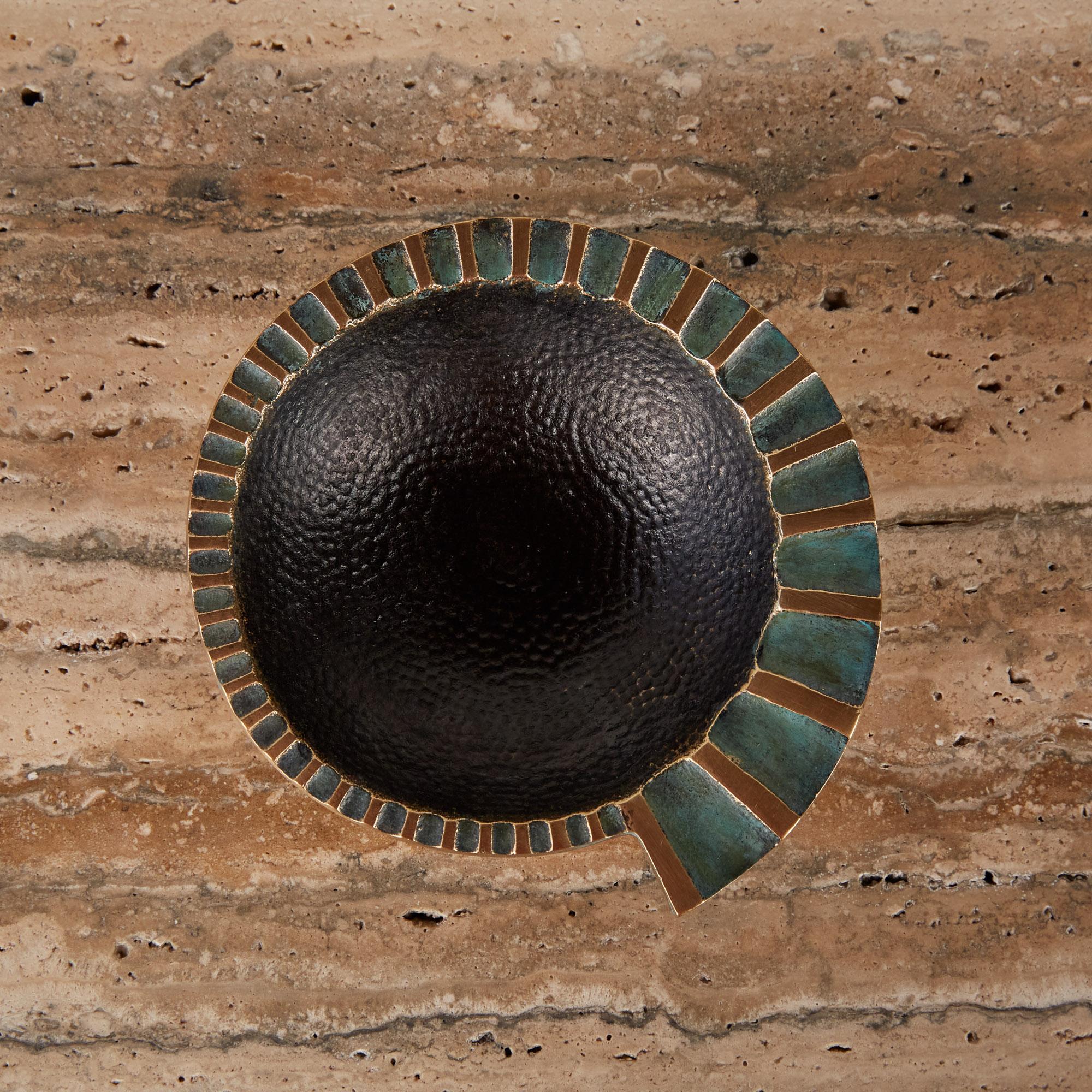 A heavy, cast bronze ashtray by Maurice Ascalon in a nautilus shape has a fluted, flat edge that widens as it spirals around the well, which has a hammered texture. The concave portions of the fluting are finished with a verdigris patina that