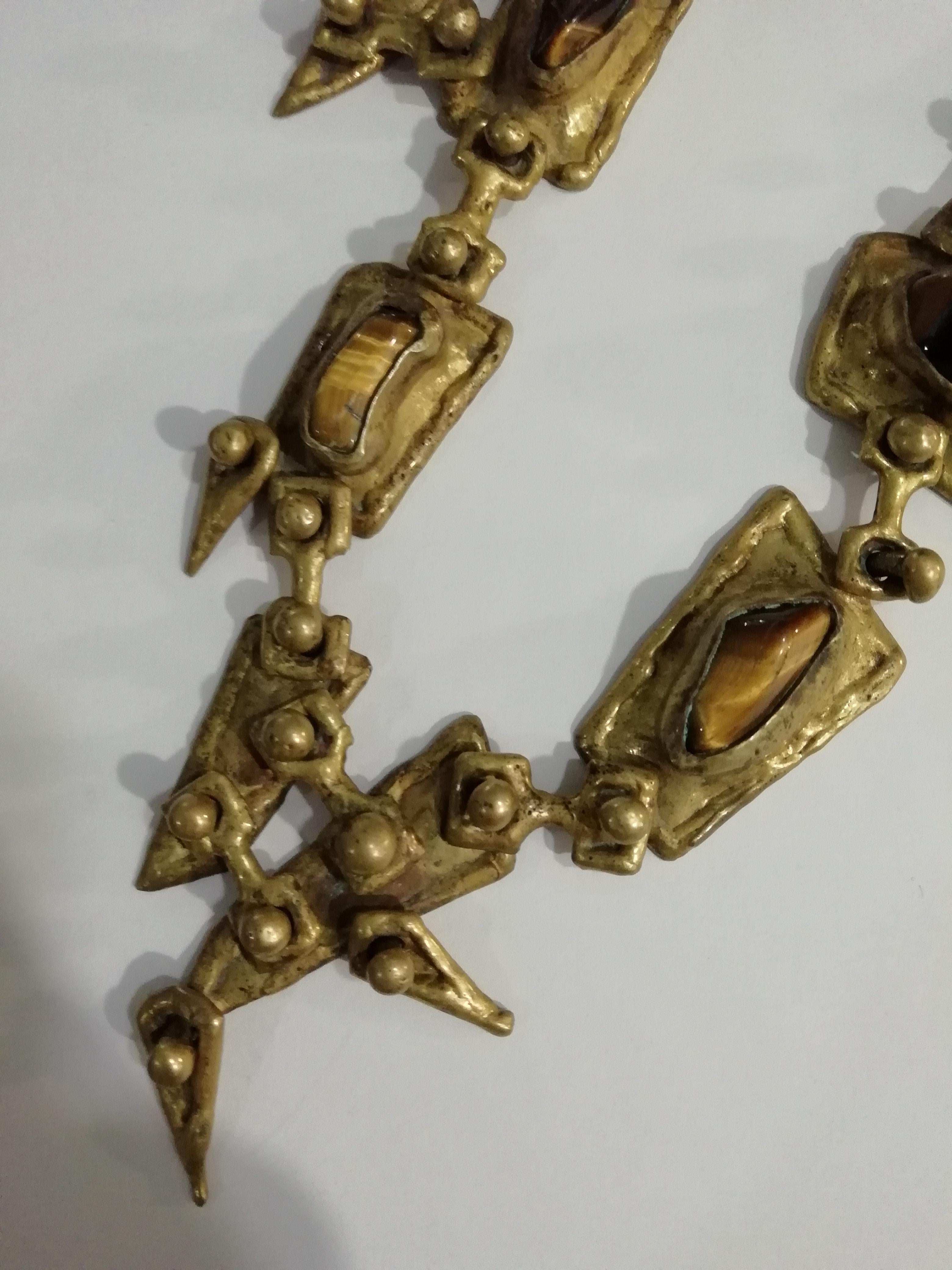 A gorgeous Brutalist style bronze necklace with tiger's eye stones by Pal Kepenyes. The necklace shows 5 irregular tiger's eye stones and geometric design with rounded motifs. Signed on back.

Sculptor from Hungary who was nationalized Mexican, he