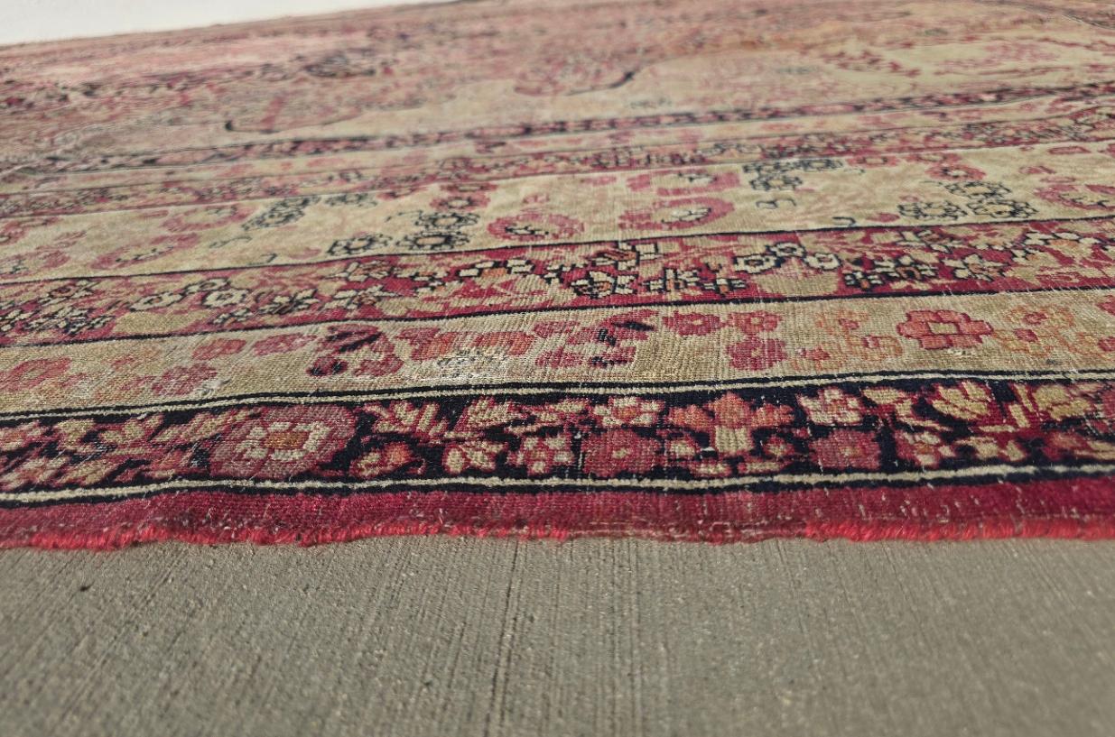 Verleihen Sie Ihrem Raum einen Hauch von zeitloser Eleganz mit diesem antiken persischen Kirman-Teppich, einem atemberaubenden Beispiel für handgeknüpfte persische Kunstfertigkeit. Dieser 12 x 15 cm große Wollteppich wurde in Kirman, Persien,