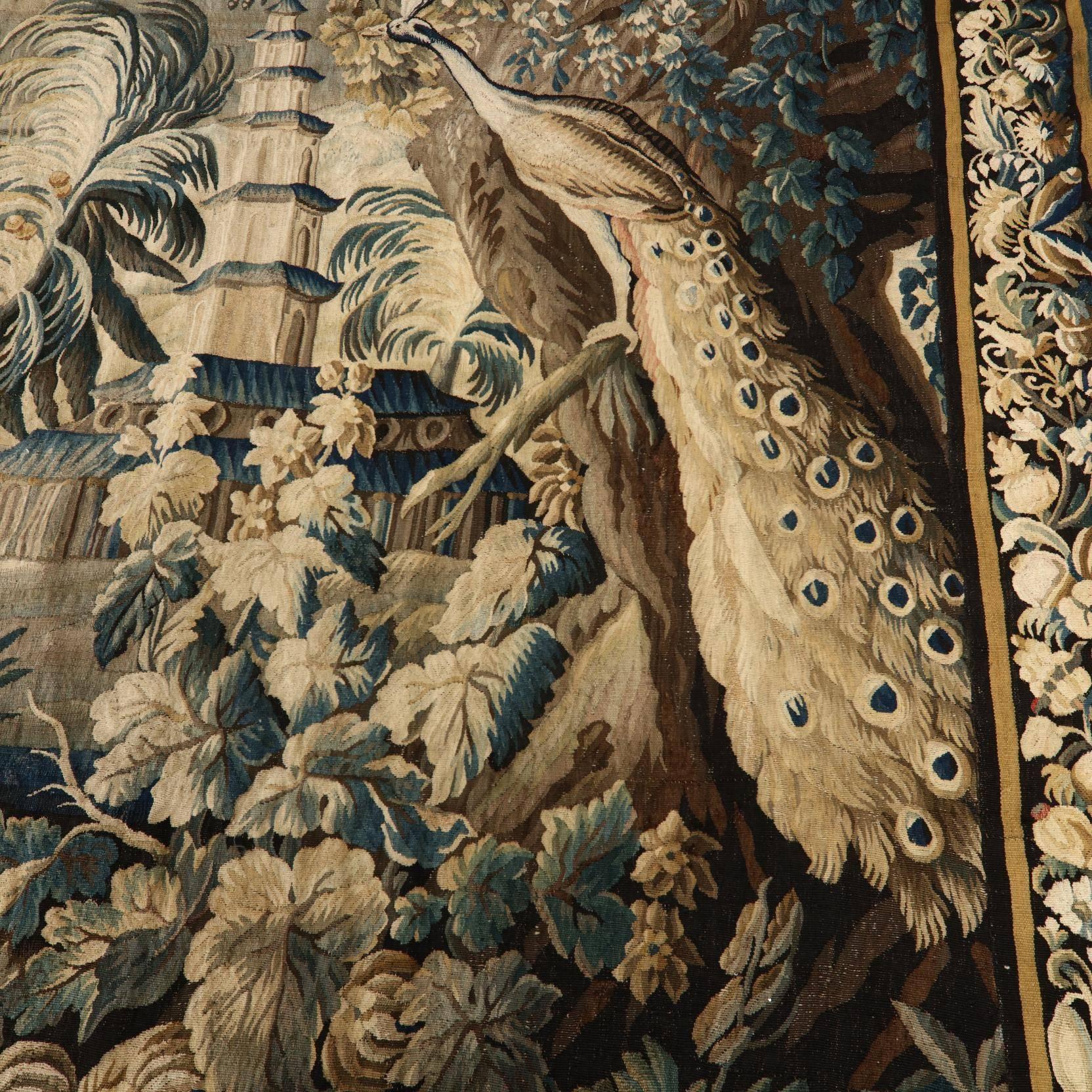 The exotic landscape centred with a Chinese pagoda with architectural design elements among flowering foliage and avian motifs and peacock to a corner, with dark blue border with scrolled and floral design, circa 1720.