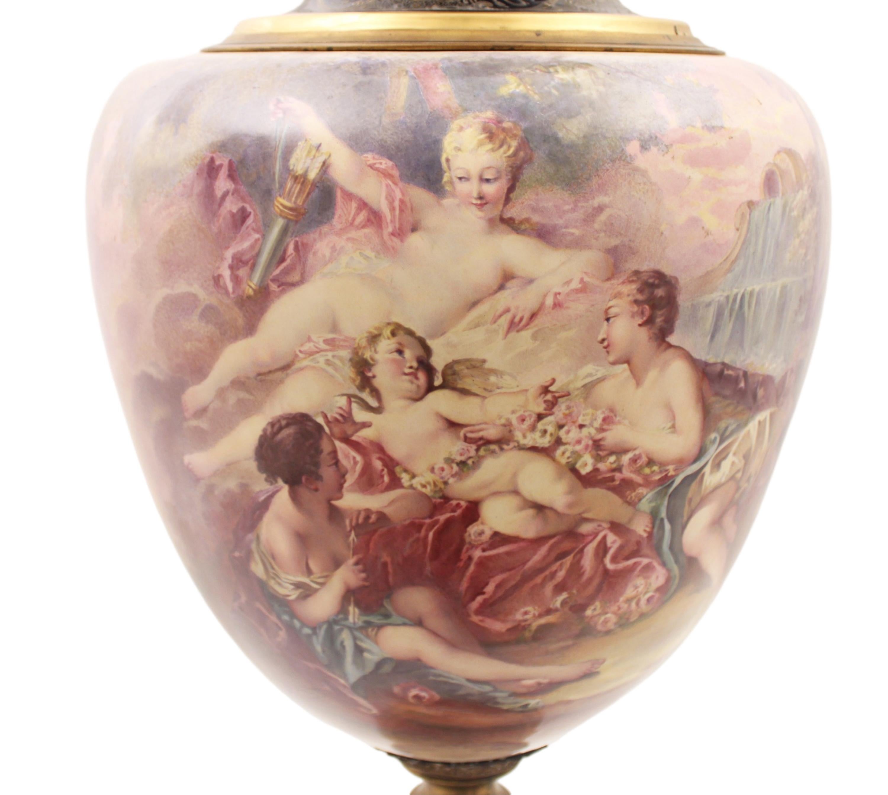 Palacial French Sevres vase with cover, having pomegranate gilt bronze finial over a cobalt blue and gilt overlay lid, neck, and foot, the main body vignette depicting angelic figures attending to cupid reclining among floral wreaths and clouds,