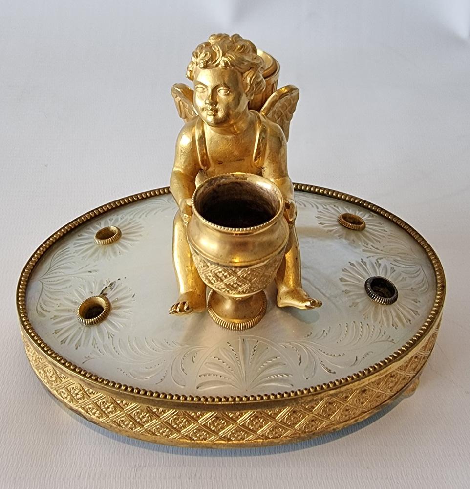 Palais Royal mother of pearl and ormolu inkwell depicting Cupid. Set upon a fine ormolu base with four ormolu feet, with the very finely engraved mother of pearl base sitting on this. In the centre sits a finely detailed Cupid, holding a vase