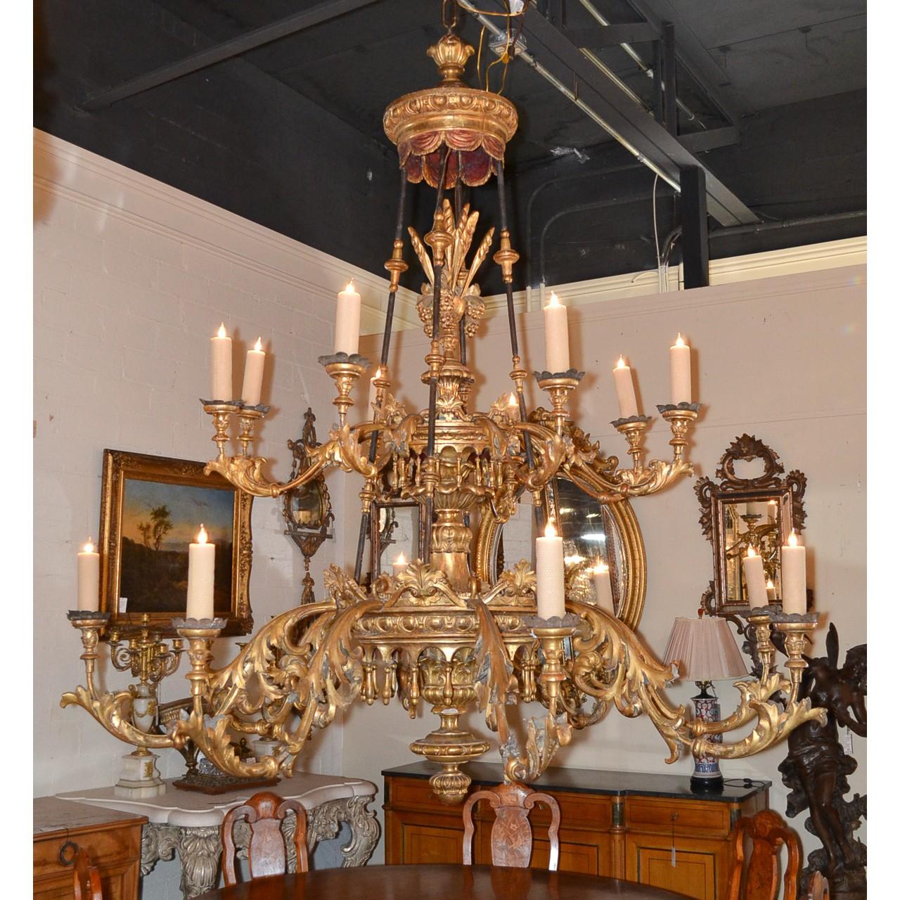 Extraordinary and large 19th century French hand-carved giltwood chandelier with a curtained crown atop carved wheat sheaves and grape clusters. The stem with superbly detailed acanthus leaf carvings displayed in scrolling fashion and accented with