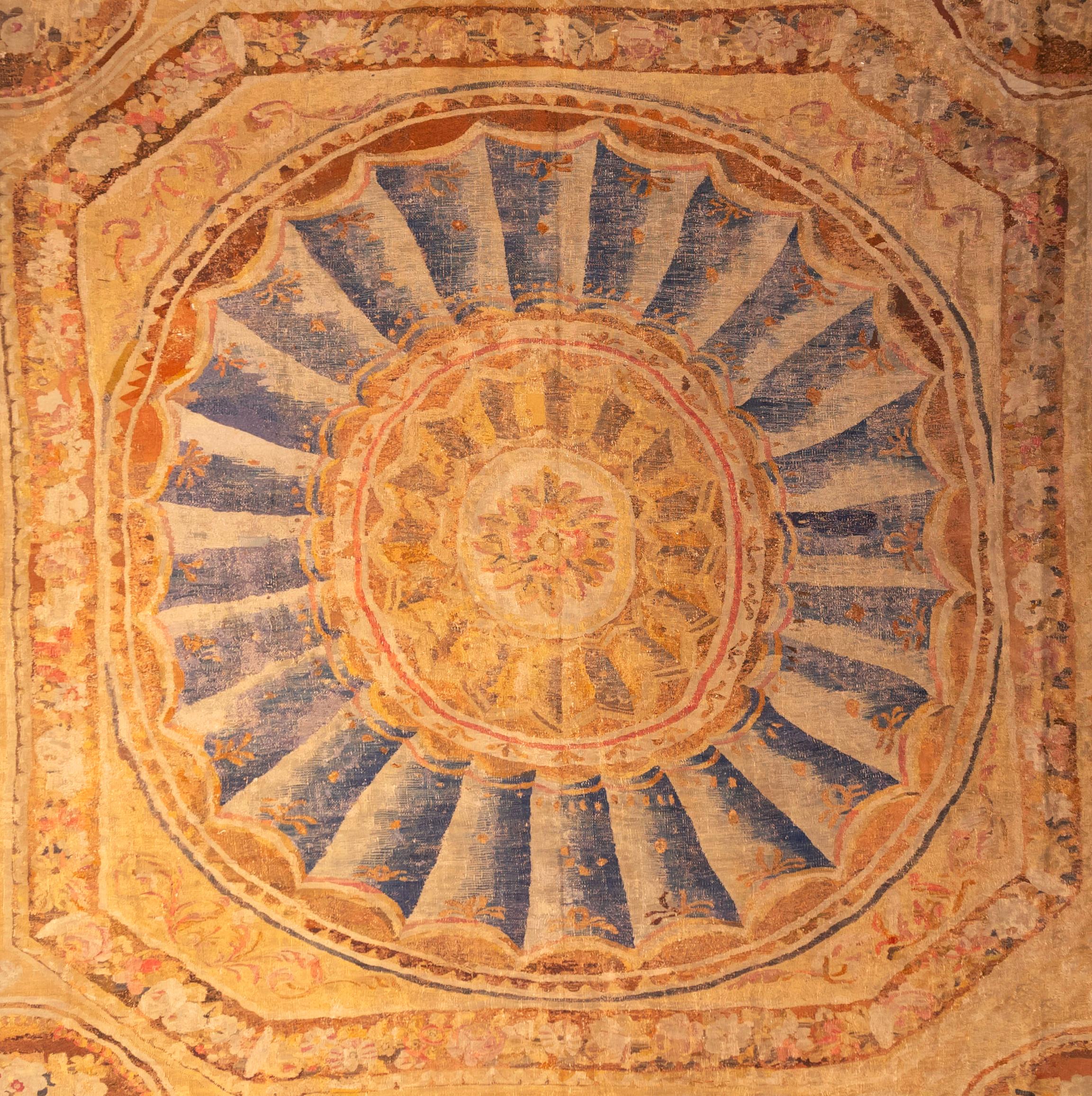 Ein erhabener, quadratisch gewebter französischer Teppich aus dem 18.  Ein zentrales Medaillon mit konzentrischen Paterae in Blau- und Olivtönen ist von vier floralen Eckmedaillons umgeben.  Alles eingefasst in einen Rahmen aus Palmetten und