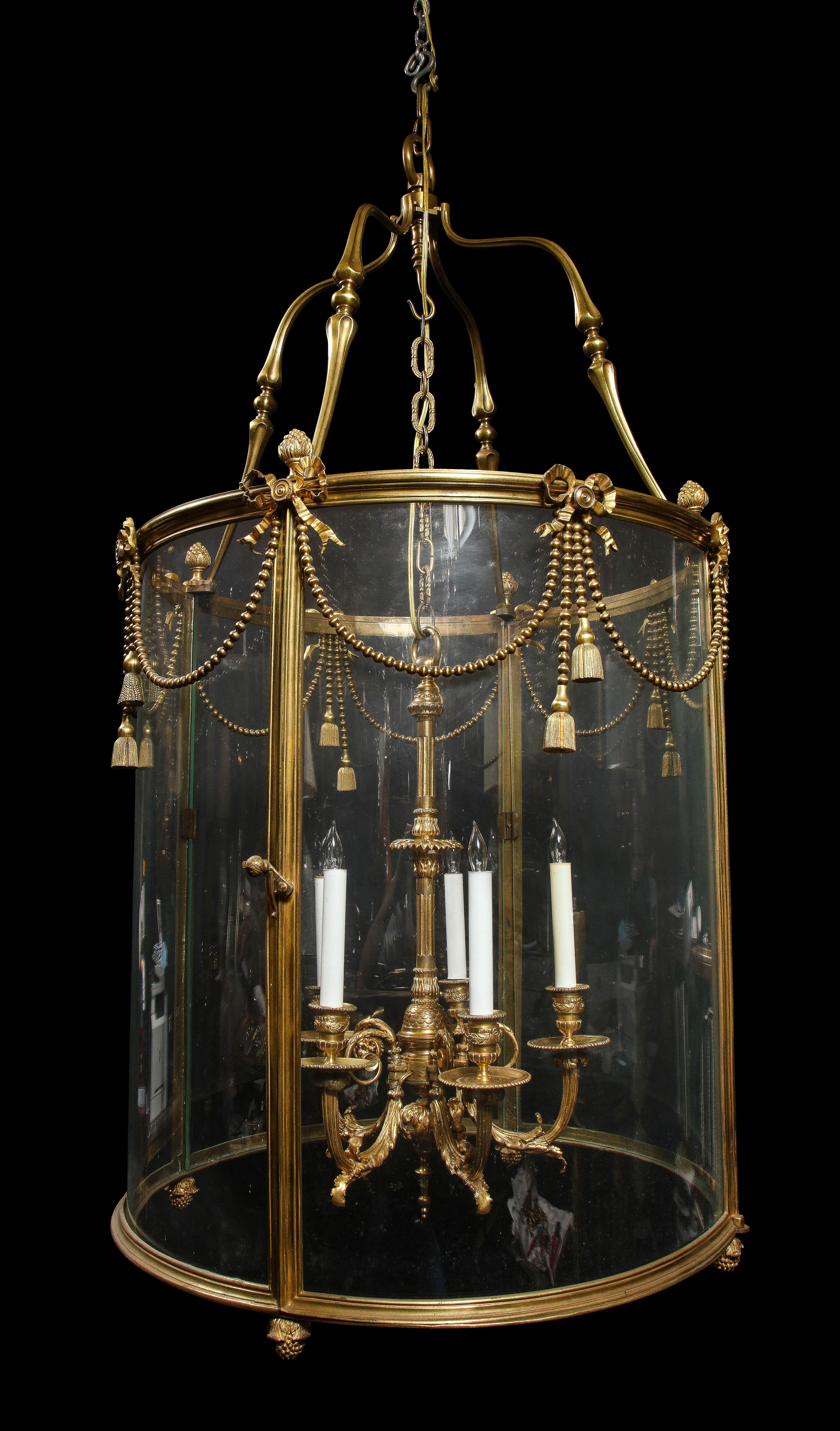 A palatial and monumental large antique French Louis XVI girl bronze multi light lantern of superb quality embellished with gilt bronze ribbons, tassels and further adorned with interior gilt bronze arms of exquisite detail.