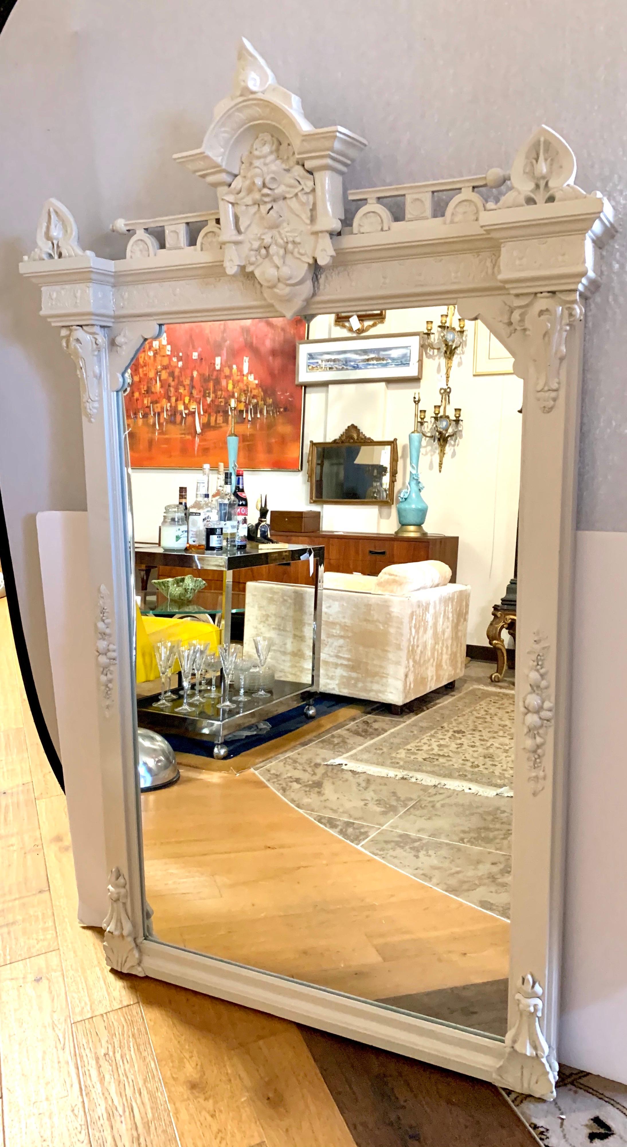One of a kind hand painted white American Gothic mirror that is large enough to function as a
floor mirror or a wall mirror. The scale, measuring sixty four inches tall, is magnificent and the carvings
through are jaw dropping. A mirror that will