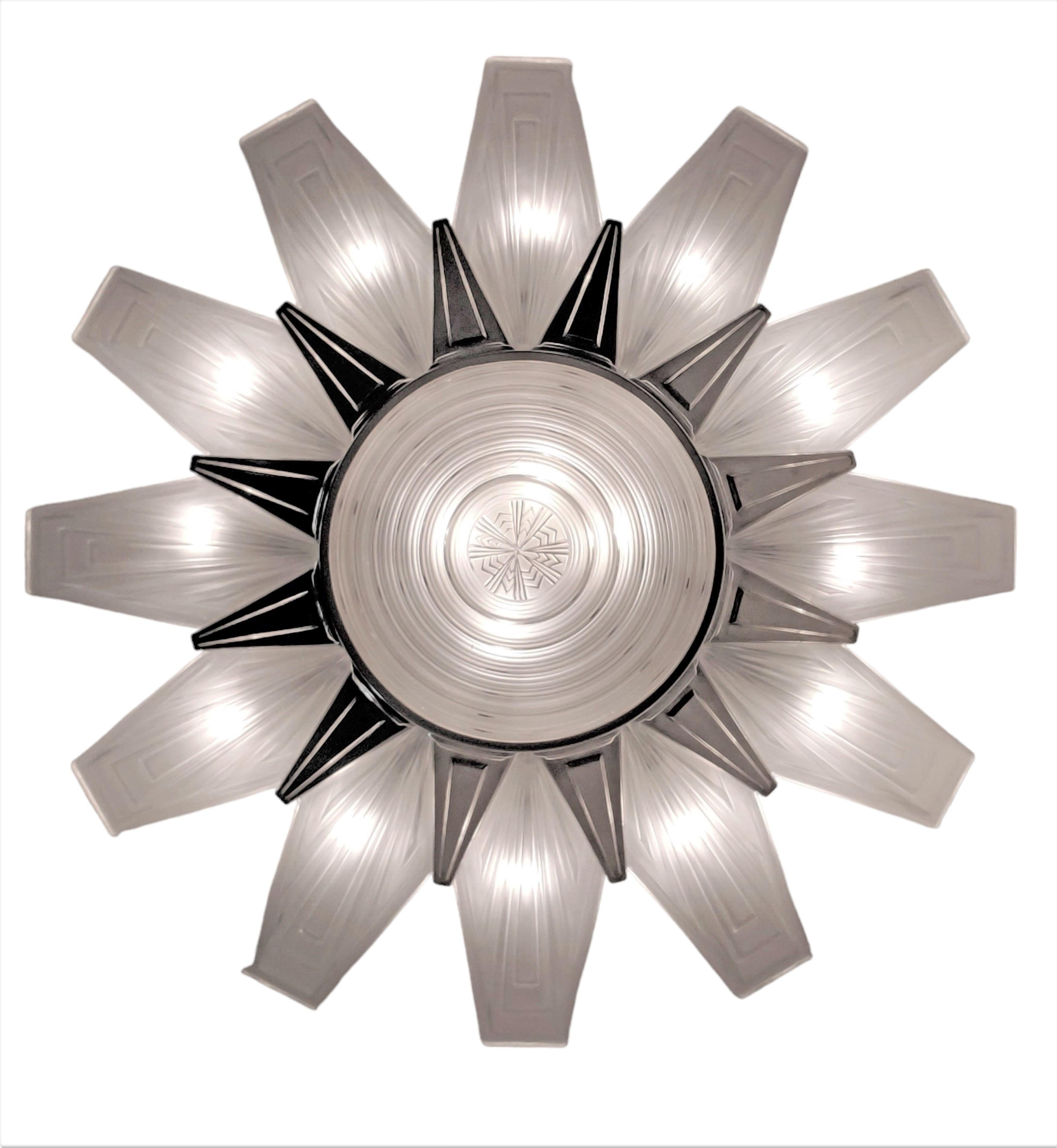 Un très grand et impressionnant lustre Art Déco français présentant douze panneaux en verre d'art dépoli s'étendant vers l'extérieur à partir d'un coupé central étagé, signé Leleu. La forme en étoile est soutenue par une suspension de six tiges