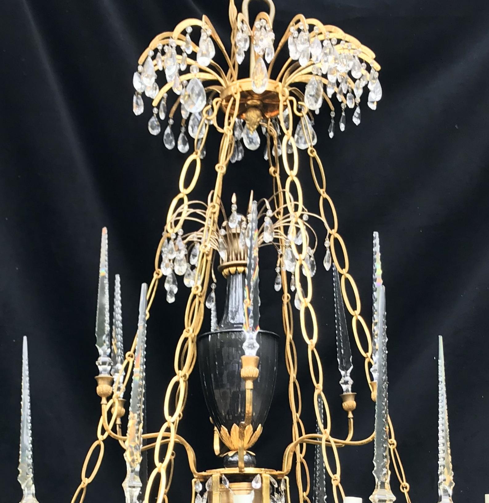 A wonderful palatial Baltic 19th century Russian neoclassical bronze and crystal twenty five-light chandelier with porcelain urn centerpiece and surrounded by cut crystal spikes finished with a crystal basket on the bottom and bronze pineapple