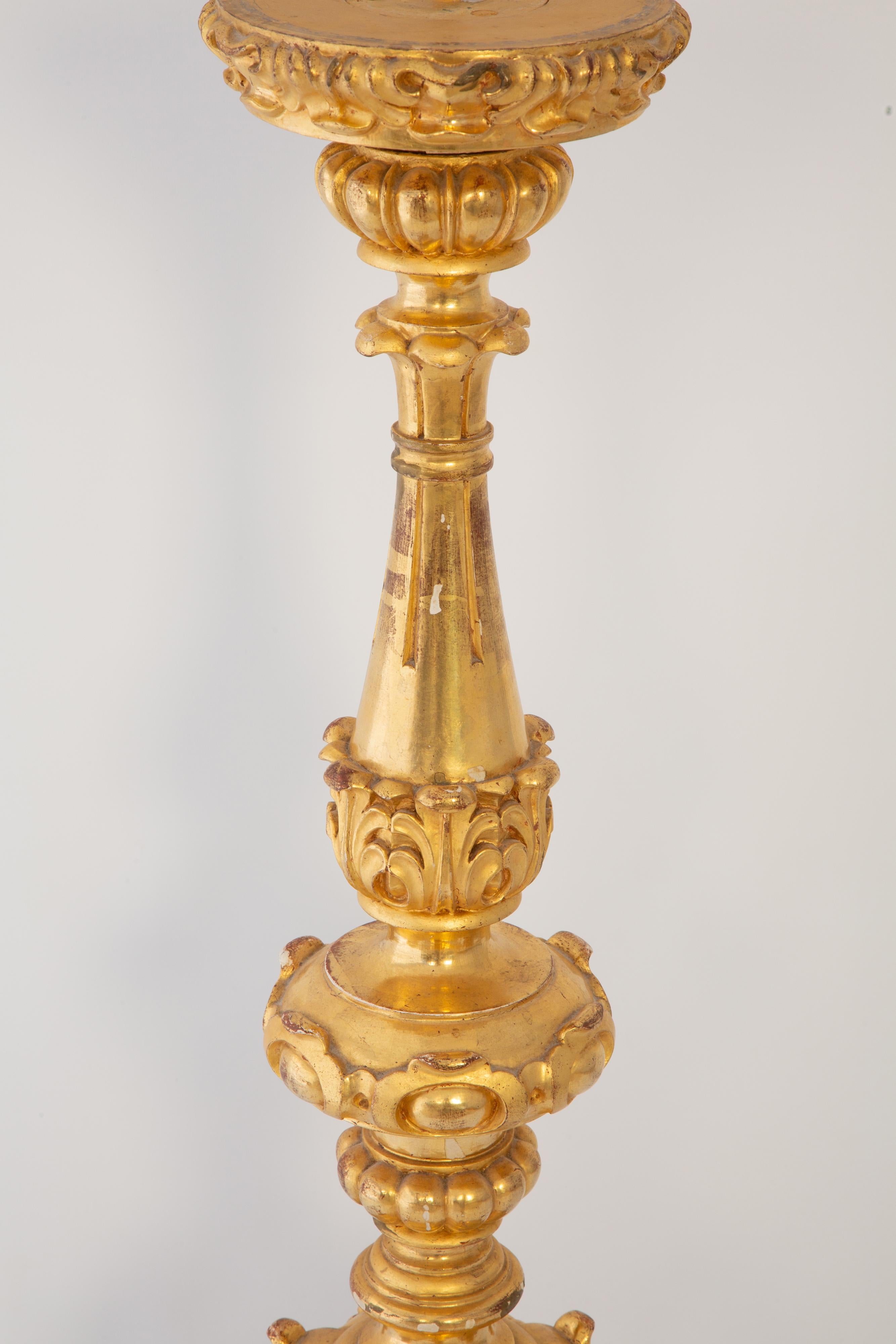 A monumentally proportioned alter pricket stick, of hand-carved giltwood. Its knopped body decorated with acanthus, beading, reeding, and elaborate scrollwork. Raised on a tripartite base with scrolling feet. 

Base Diameter: 12.25 in
Top Diameter: