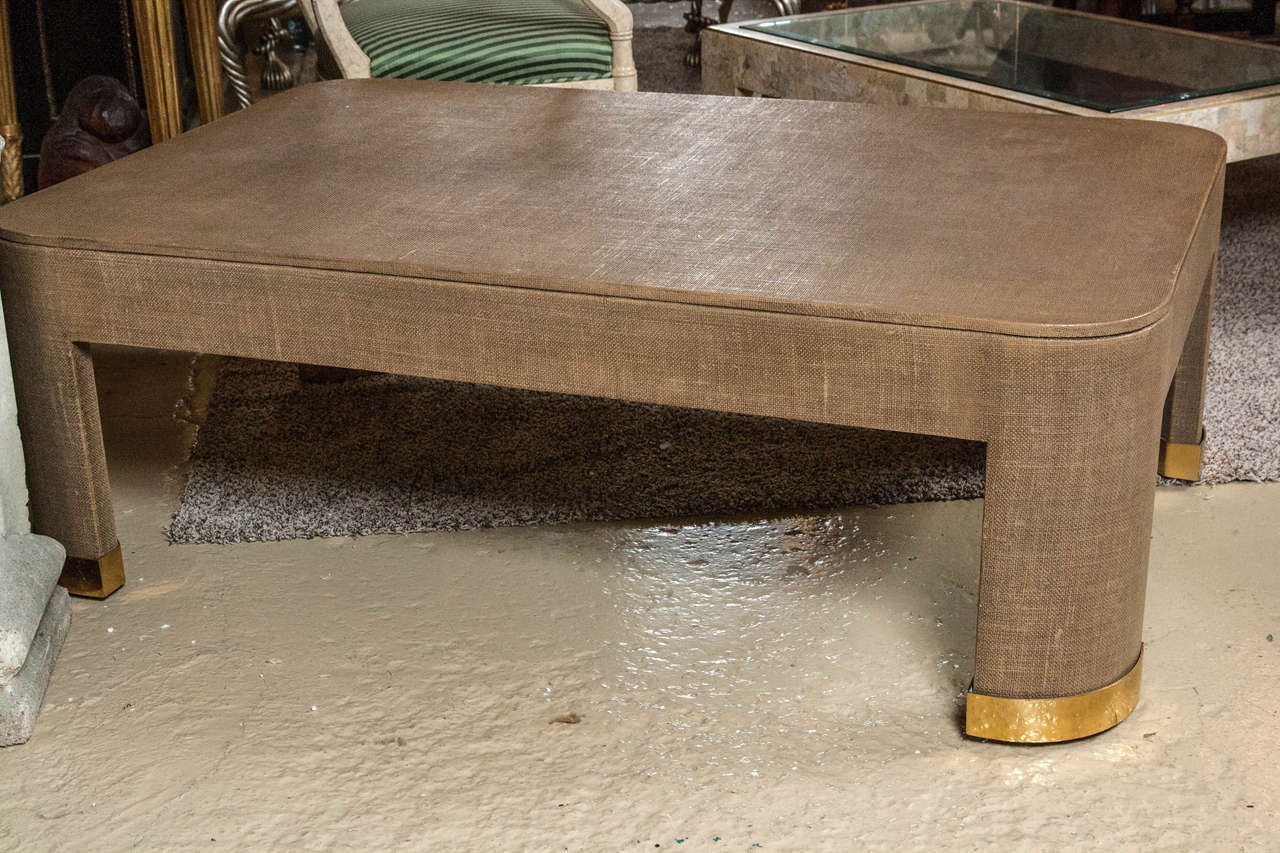 Parsons style coffee table covered in two-tone camel color lacquered linen with brass inlays in the style of Karl Springer, American, 1980s. Solid Mid-Century Modern.