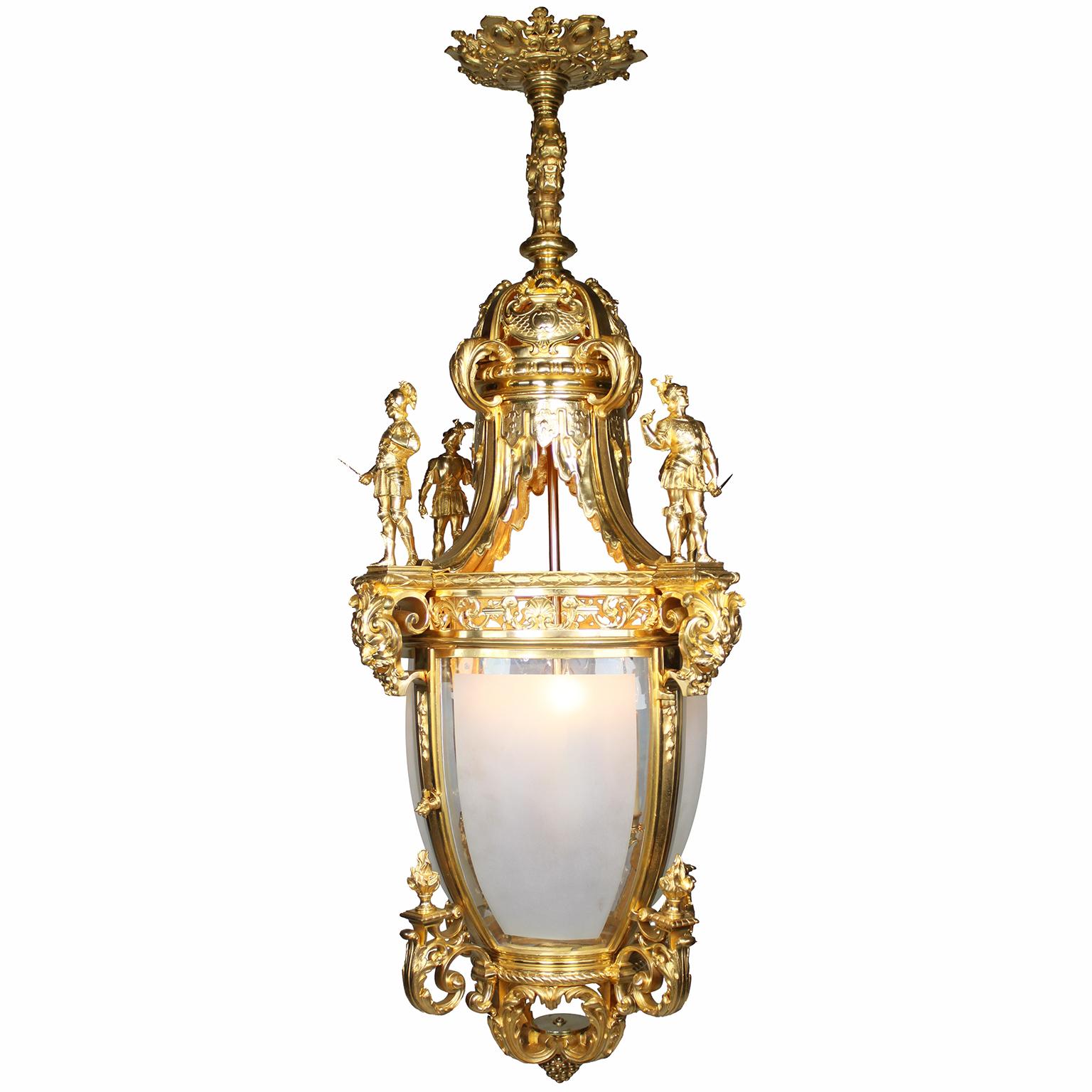 A Very Fine and Palatial Pair of French 19th/20th Century Régence Revival Style Gilt-Bronze (Ormolu) Four-Light Figural Lanterns. The impressive pair of lanterns with a pierced circular strap-work corona above a lion-mask handle, surmounting a