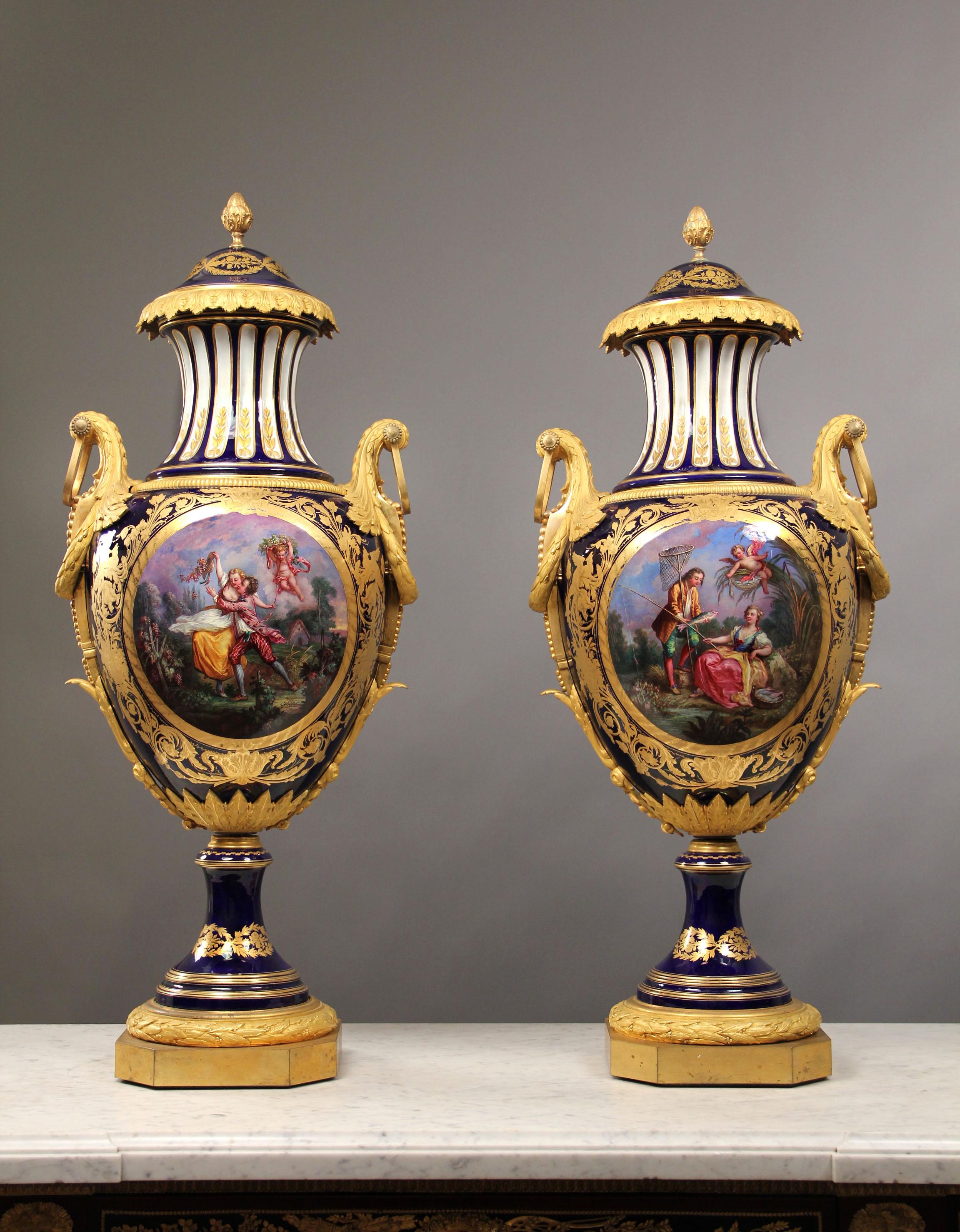 A palatial pair of late 19th century bronze mounted Sèvres style cobalt blue porcelain vases and covers

Each of baluster form with domed cover with pine cone finial, above a waisted neck and bulbous body finely painted with Watteau-esque scènes