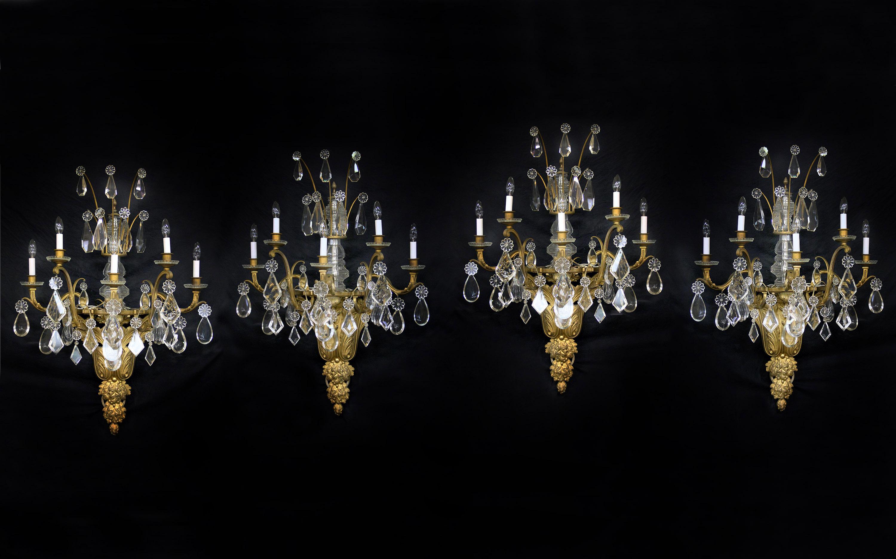 A fantastic and palatial set of four late 19th century gilt bronze and Baccarat crystal five light sconces

Wonderful quality bronze foliate designs, multifaceted and shaped crystal, cut crystal central and upper column, bobeche cups with five