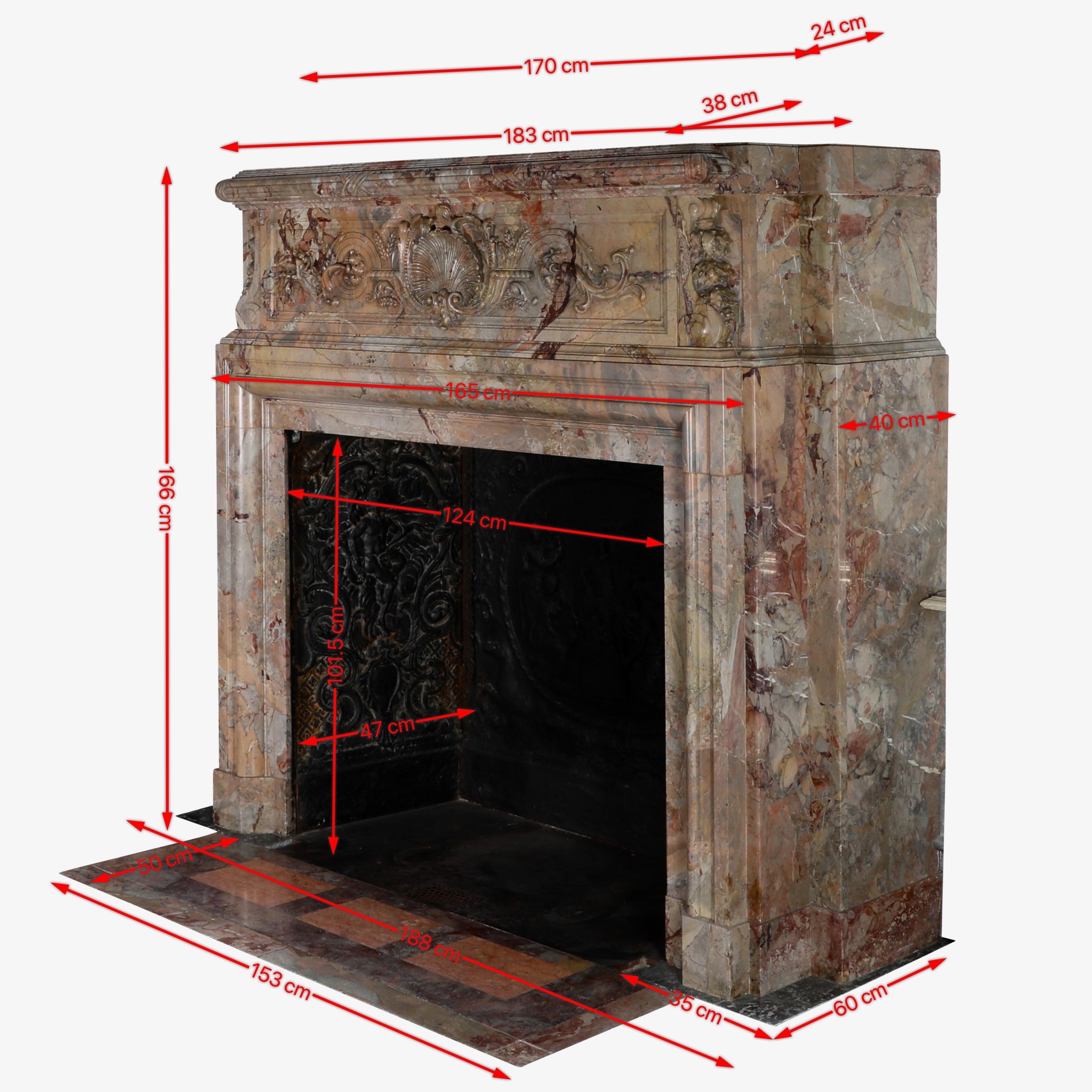 Questo splendido caminetto d'epoca del XVIII secolo, scolpito nell'esclusivo marmo Royal Sarrancolin Fantastico, presenta intricati intagli e decorazioni, tra cui un motivo centrale a conchiglia e disegni floreali che aggiungono eleganza e fascino