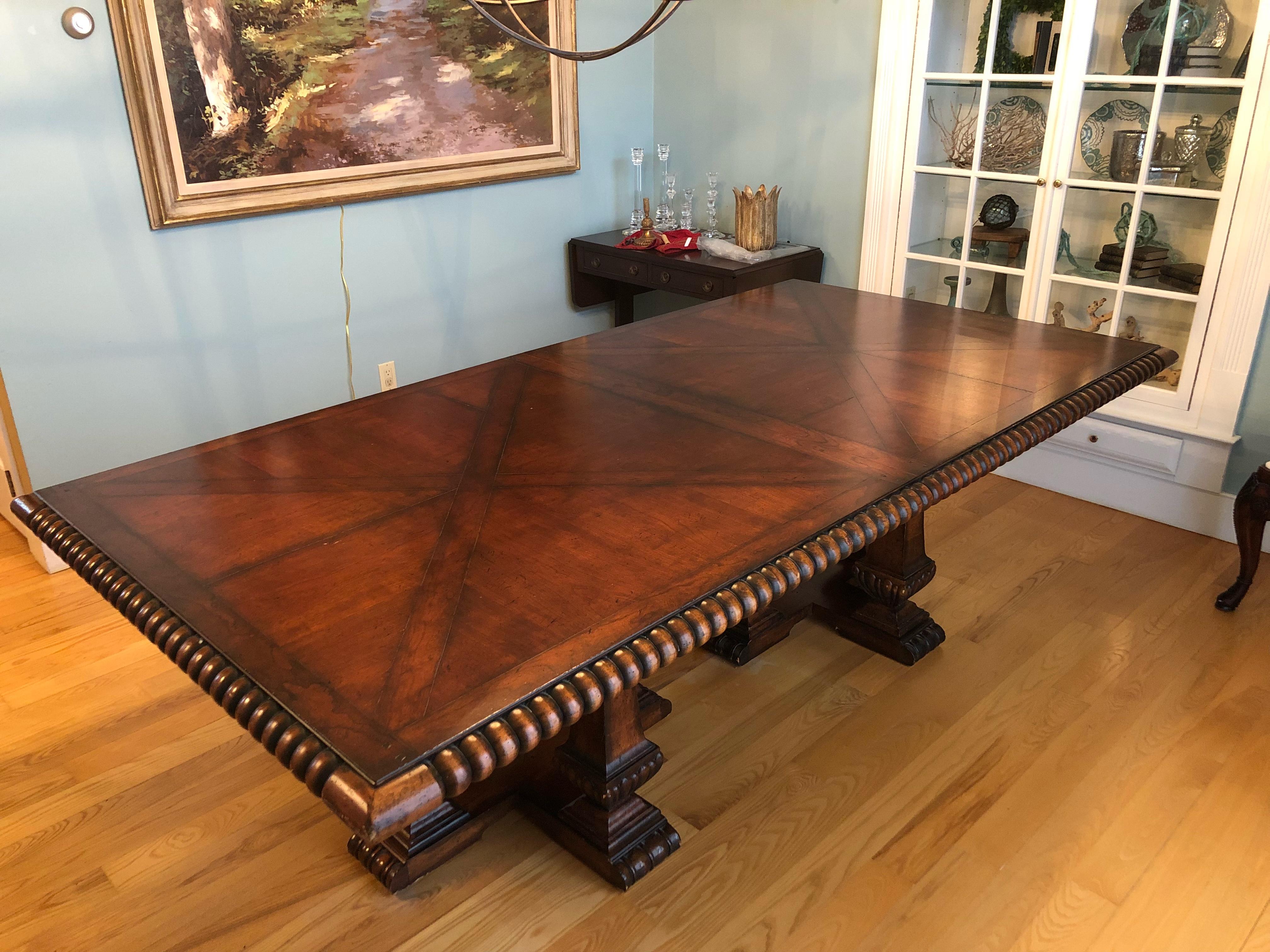 French Provincial style designer mahogany dining table having a parquetry inlaid huge rectangular top with barley twist molded edges on top of four pedestals on each end, each in the form of an obelisk mounted on a fluted urn.
Two leaves that