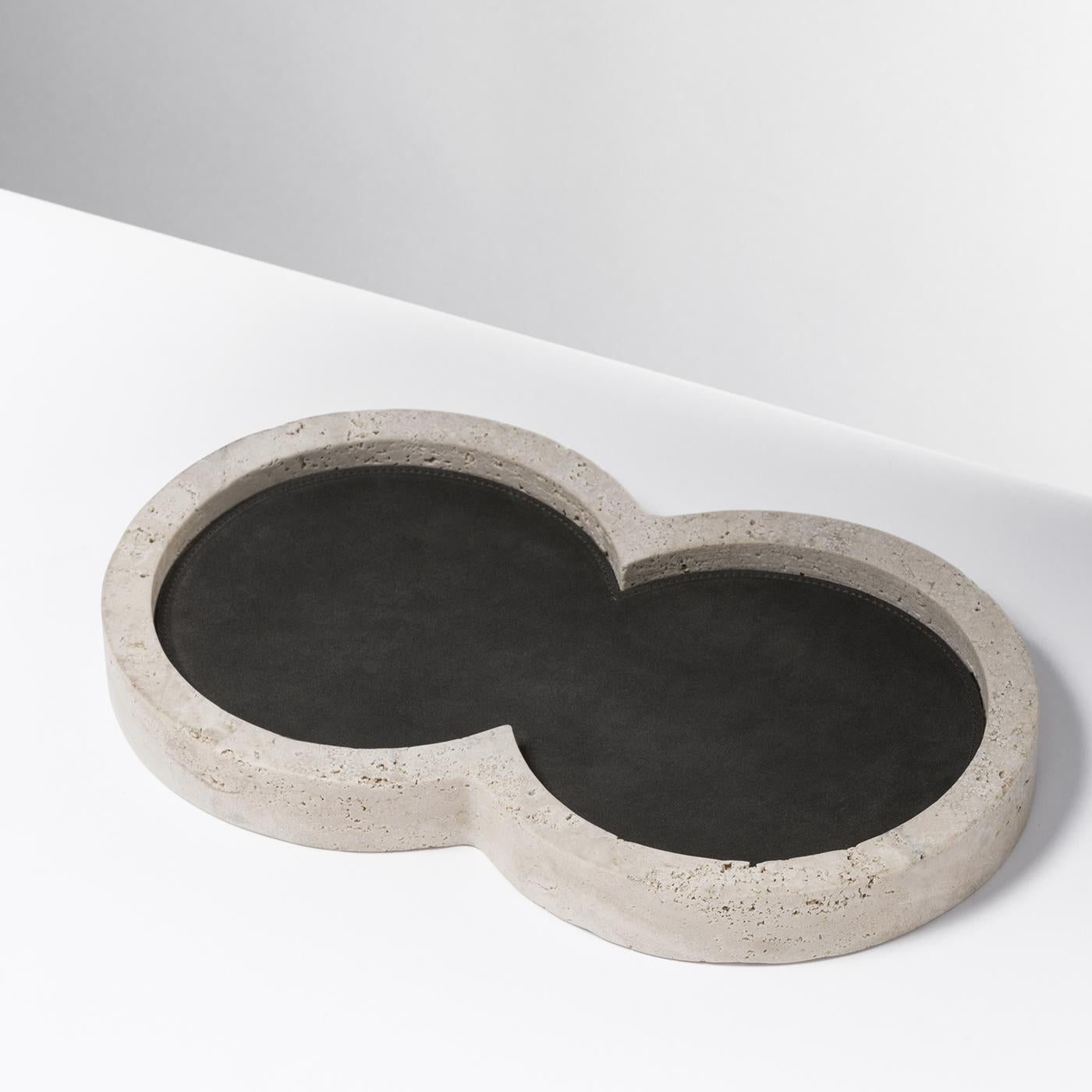 Striking in its simplicity, this valet tray is a sophisticated addition to an entryway. The original figure-eight silhouette is made entirely of cream-colored travertine limestone, a prized Italian stone. The frame is lined in black nappa leather, a