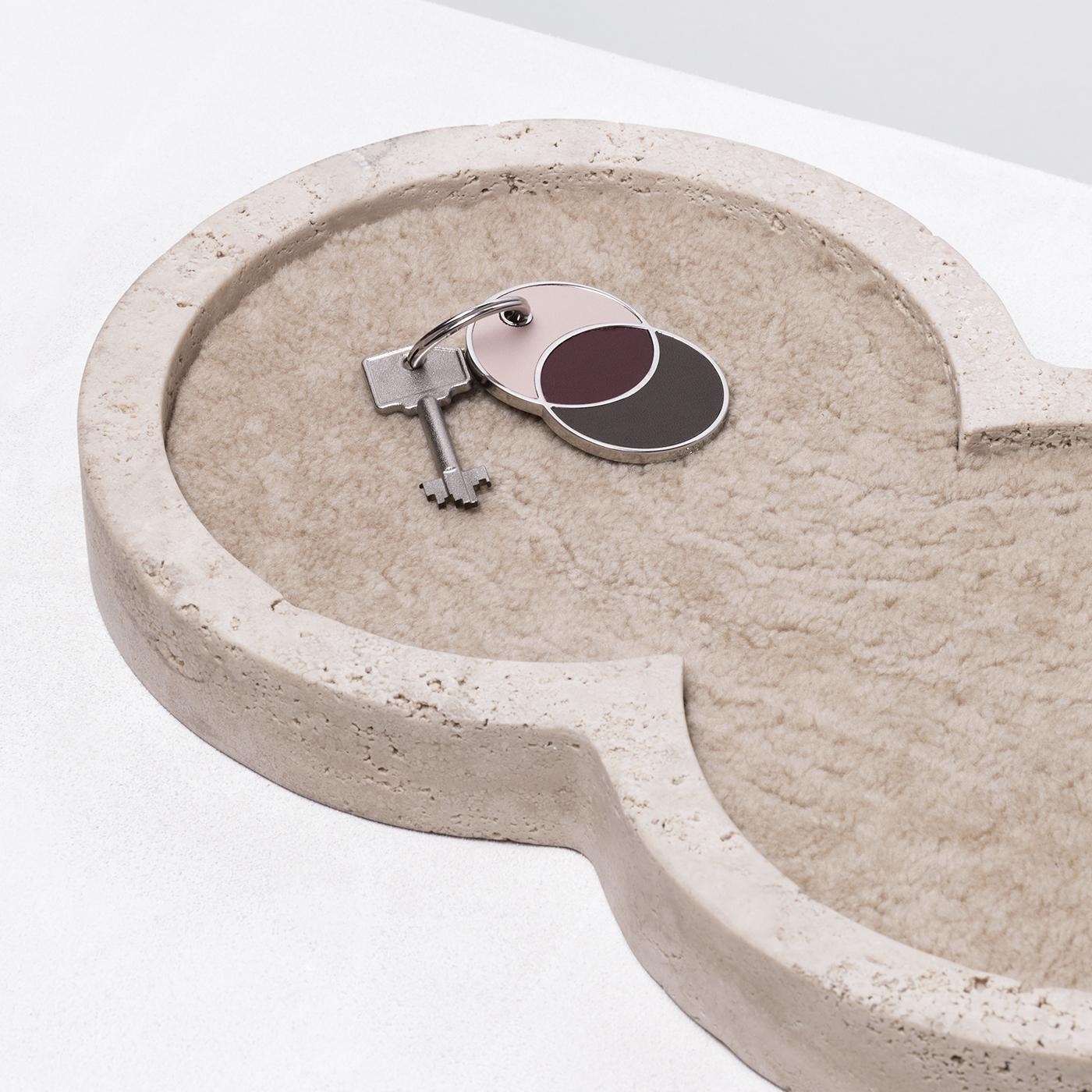 Expertly crafted in a distinctive figure-eight formation, the geometric frame of this refined valet tray is made entirely of cream-colored travertine limestone and lined in a delicate beige calfskin shearling. This harmonious combination of shapes