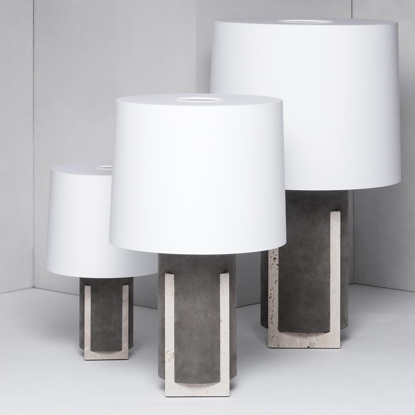 A captivating showcase of graphic sensibility, this exquisite lamp is a homage to the Classic architecture of Italian palazzos. The cylindrical body, crafted in brown nappa leather, rests atop a beige travertine limestone square base. Four