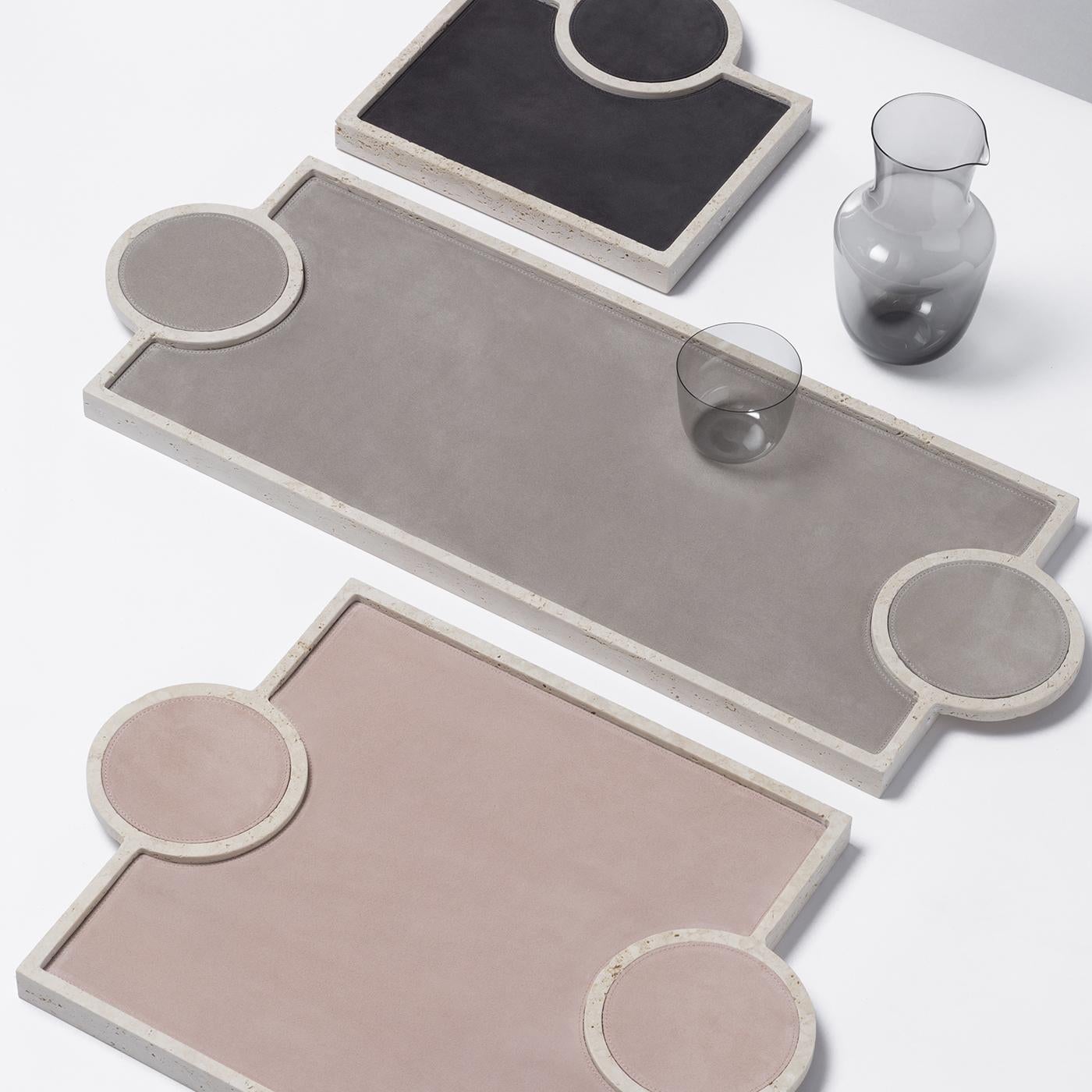 This refined tray is a sleek and modern addition to any home decor. Crafted of prized, travertine limestone, the long, rectangular frame is lined with taupe nappa leather. The tray handles are formed by two flat, two-dimensional circles embedded on