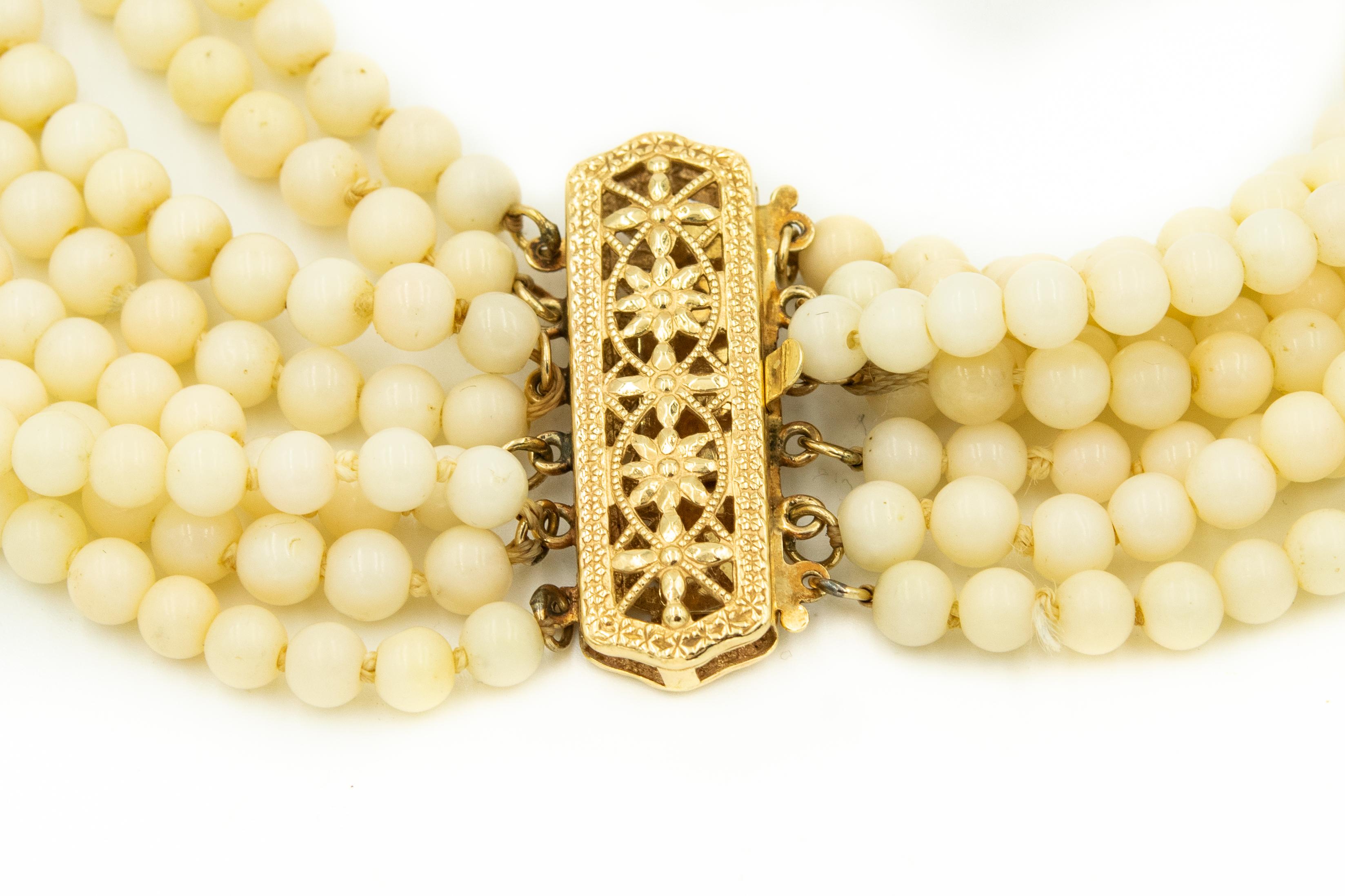 This elegant necklace features 8 strands of 4.66mm (approximately) very pale angel skin coral beads with an elongated 14k yellow gold floral flower filagree clasp.  