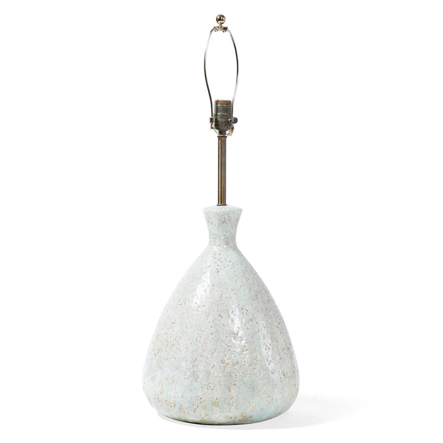 In a classic teardrop shape, this mid-century lamp combines a ceramic base with a metal armature. A reactive glaze alternates between pale blue and beige and creates a crackled, textural surface. In excellent working condition, the lamp includes a