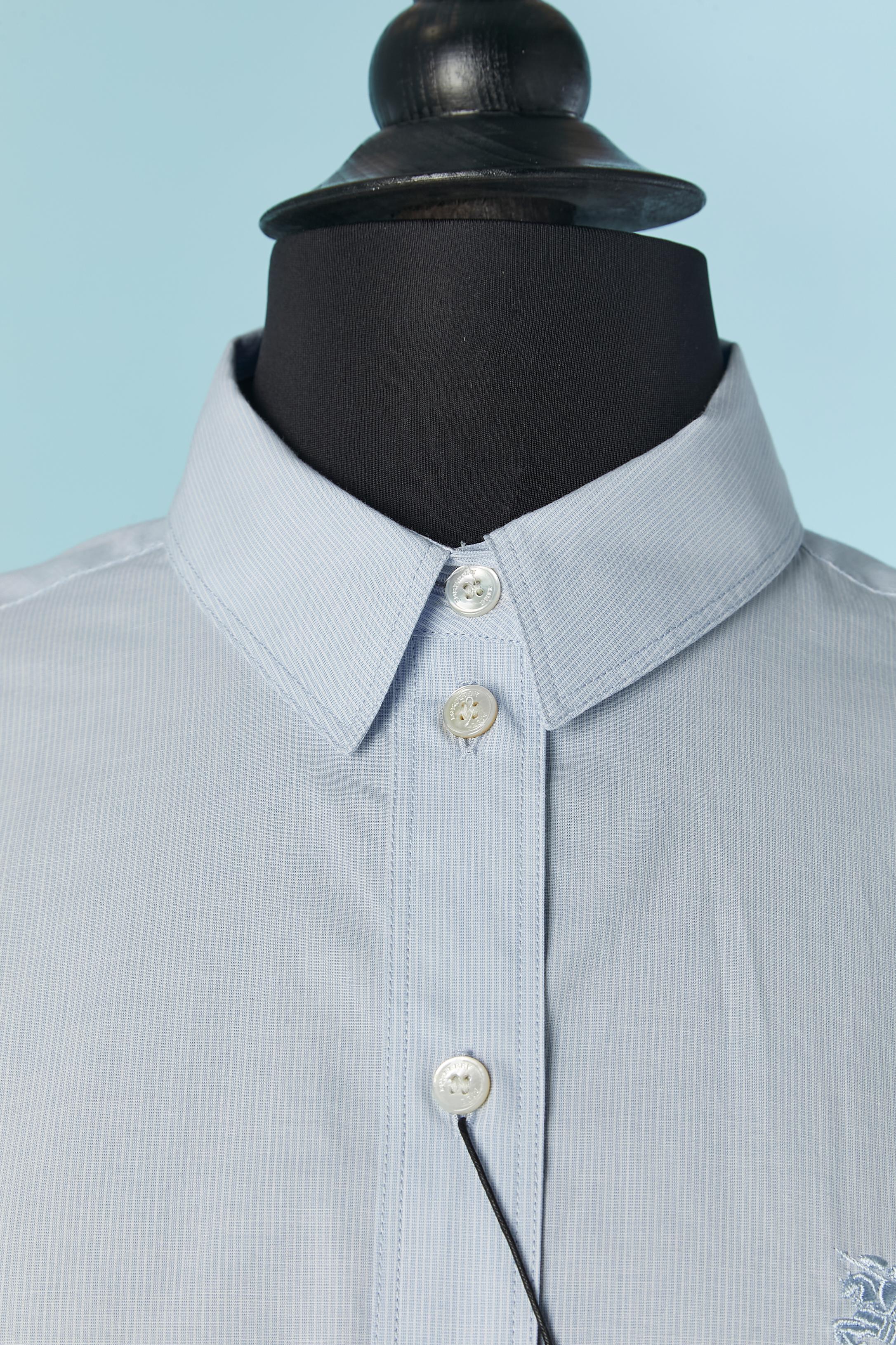 Chemise en coton bleu pâle avec de très fines rayures. Composition du tissu : 98% coton, 2% élasthanne. Bouton de marque et fermeture à la boutonnière sur le milieu du devant  et sur les poignets + 2 boutons supplémentaires fournis. 
Taille XS sur