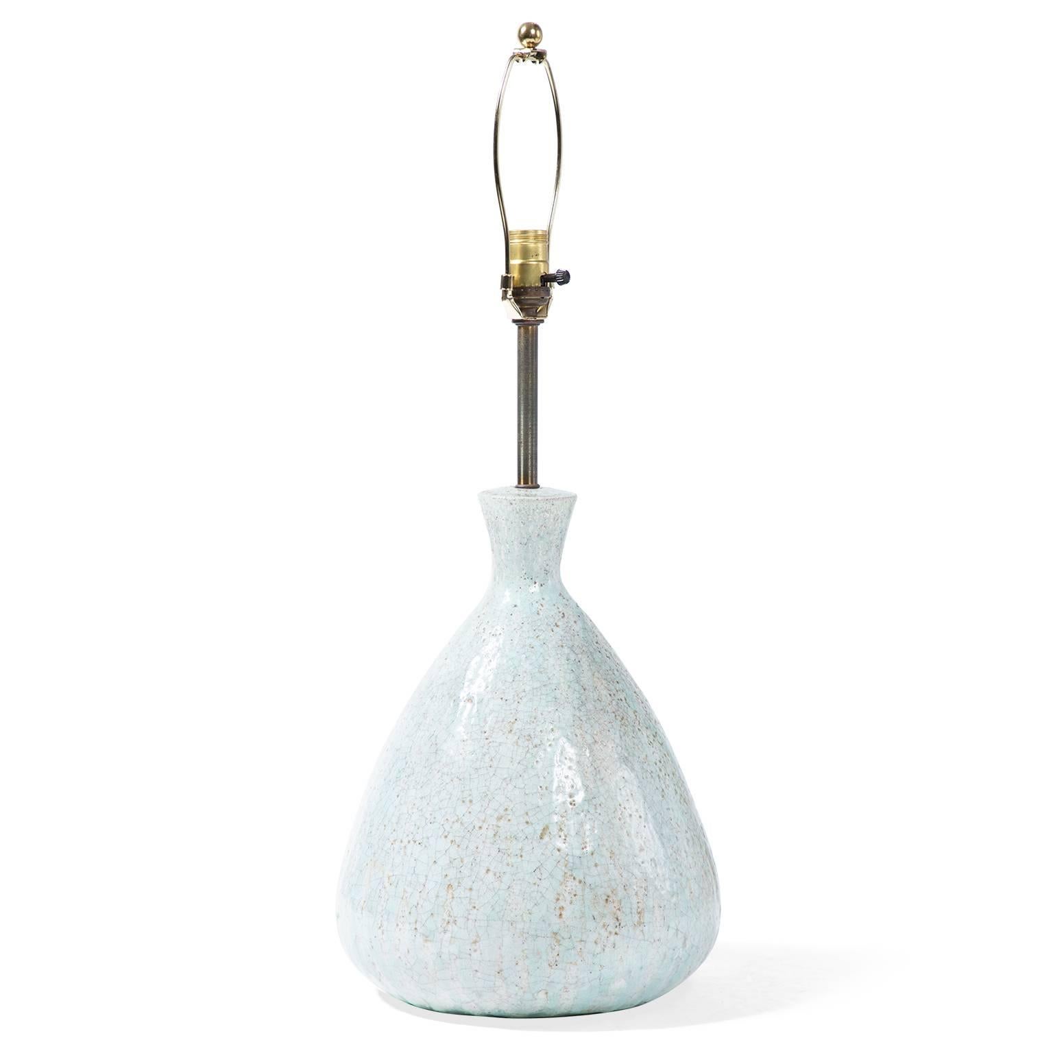 In a classic teardrop shape, this mid-century lamp combines a ceramic base with a metal armature. A reactive glaze alternates between pale blue and beige and creates a crackled, textural surface. In excellent working condition, the lamp includes a
