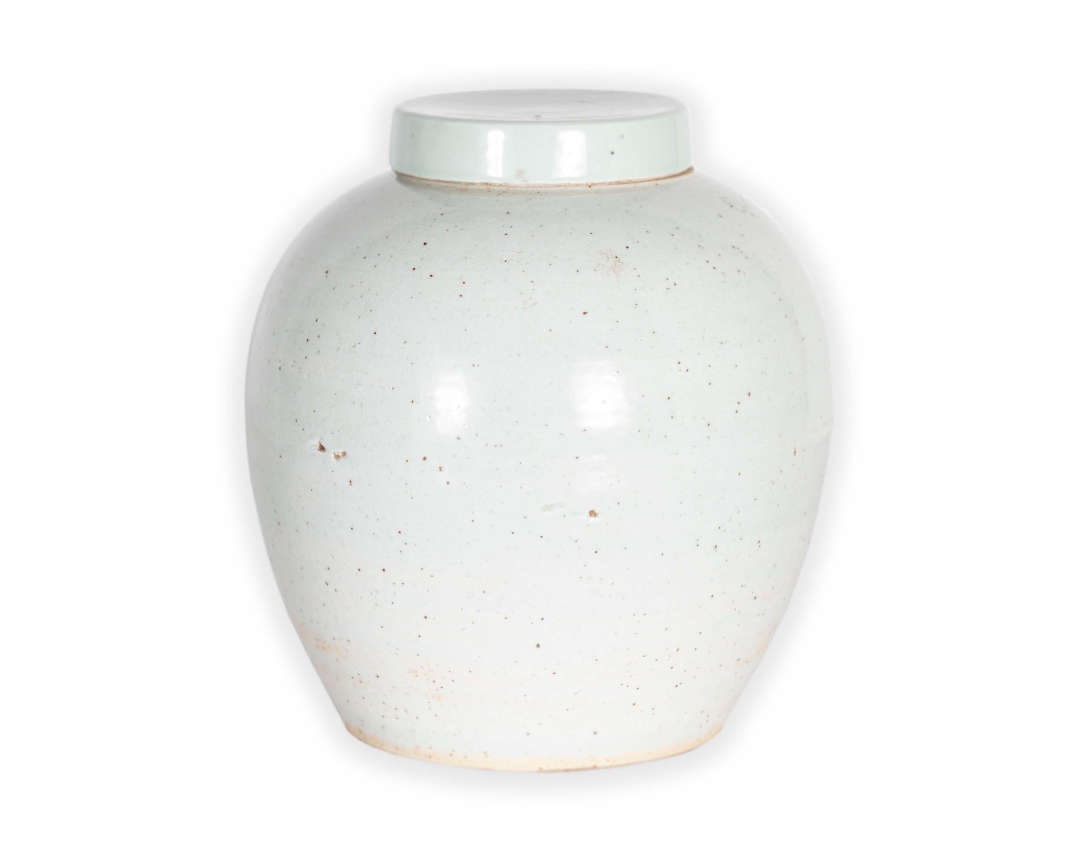 A delicate Chinese vase with a hint of color and crackle. The unique crackled glaze effect is achieved by heat-producing thermal expansion, in which minute cracks appear in the porcelain. Coated in a pale white finish that brings an air of levity to