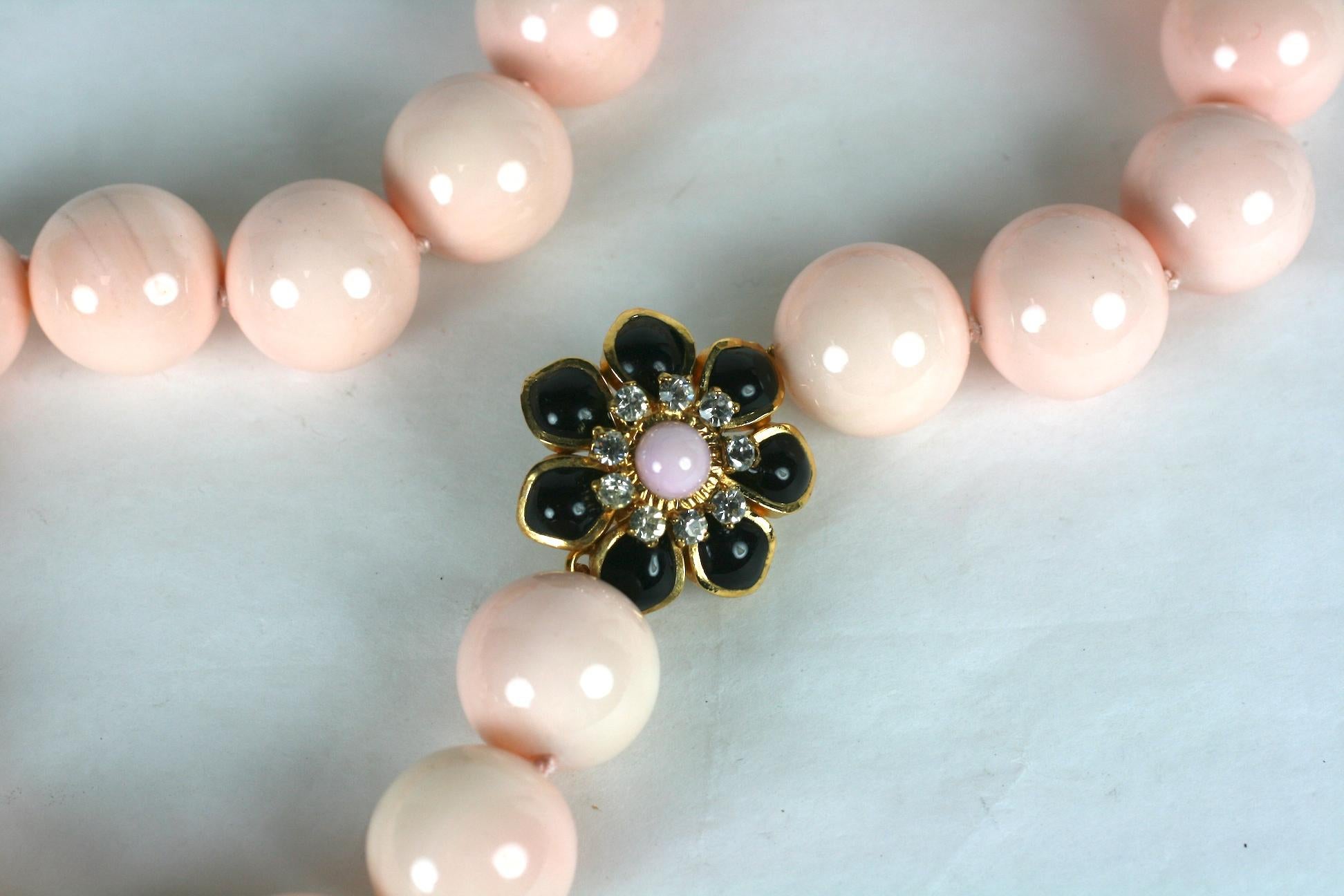 Pale coral laquered mother of pearl hand knotted beads with hand made Marguerite floral clasp in jet and pale coral poured glass enamel with crystal rhinestone accents. Hand made in our studios in France. 
