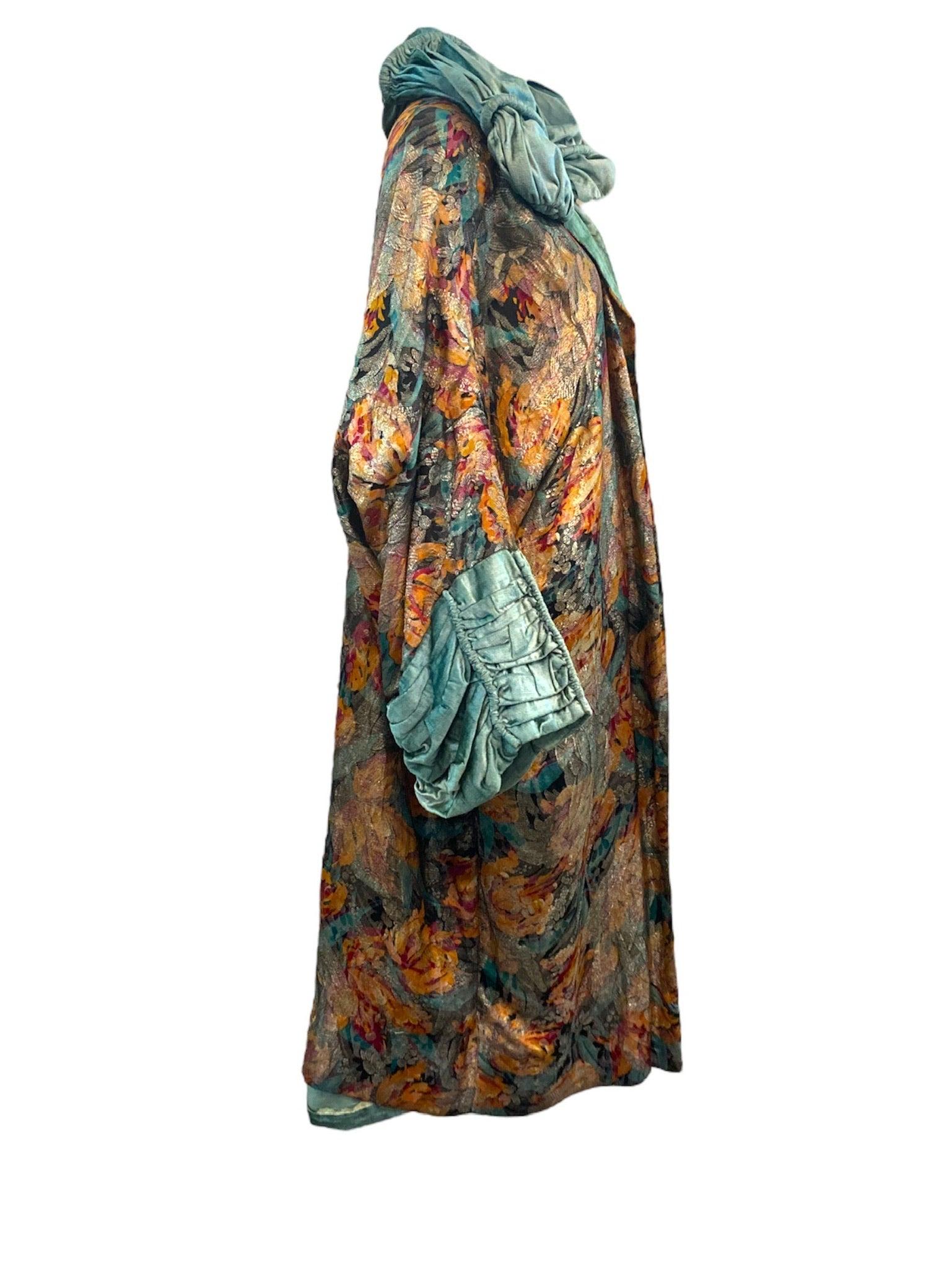 She is a rare and lovely beauty. 1920s opera coat in an autumnal toned floral lame lined and trimmed in a pale green velvet with ruched stand up collar and exaggerated  cuffs.  Open front wrap style cocoon. Femme fatale vibes with  woodland fairy